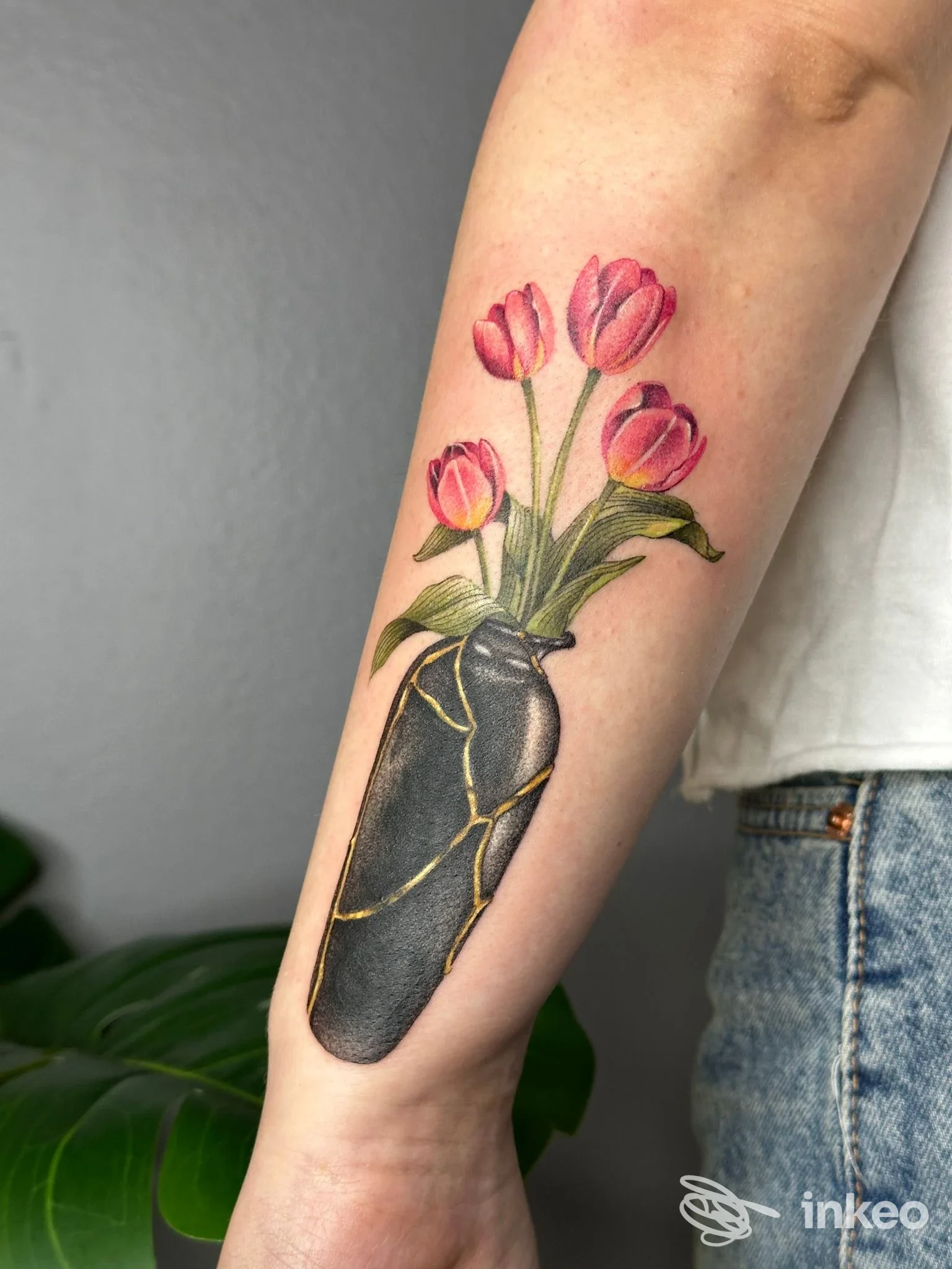 Tatuaggio su avambraccio: vaso scuro con venature dorate e tulipani rosa, Cecchitatua, Torino.
