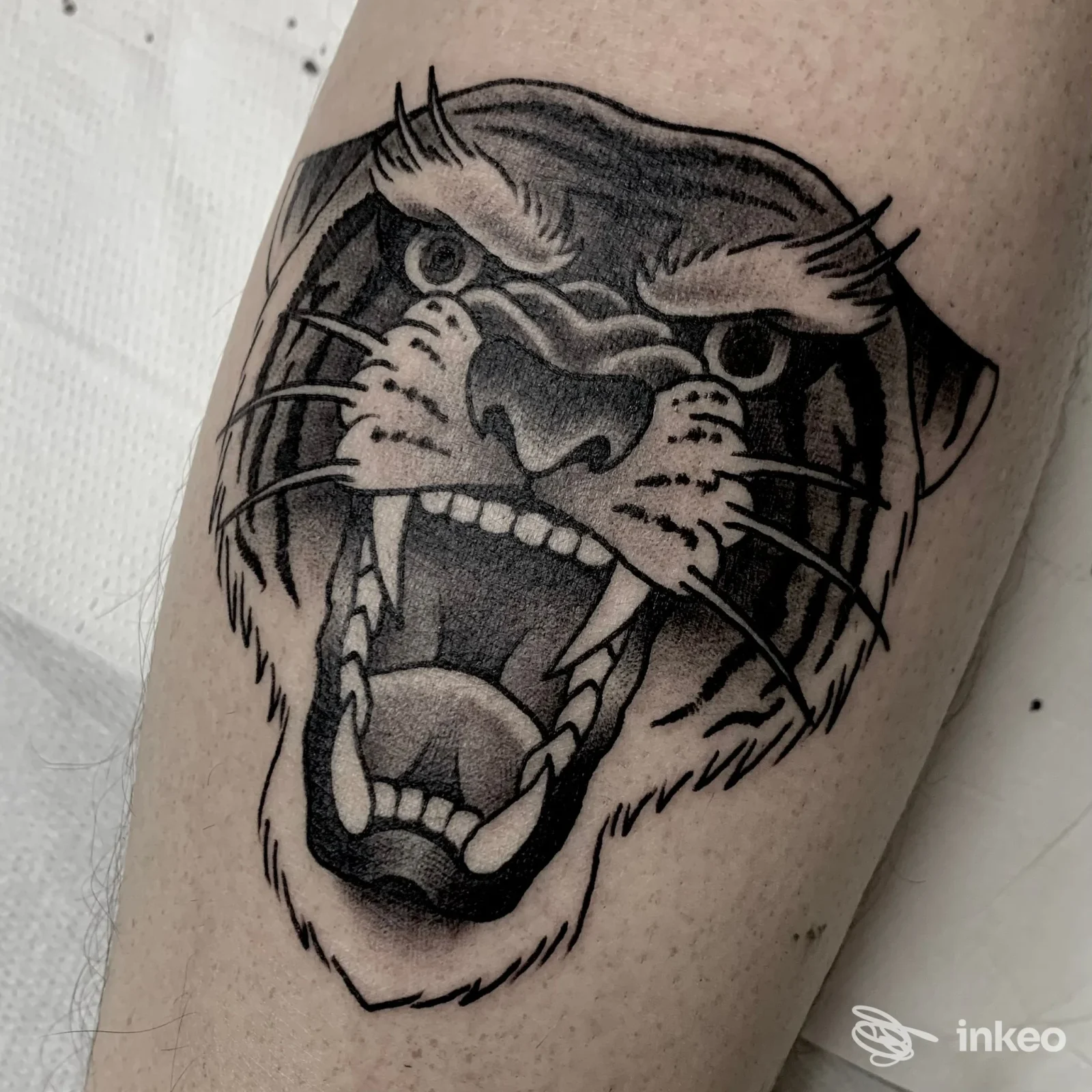 Tatuaggio testa ruggente in nero e grigio su avambraccio, opera di Cecchitatua a Torino.