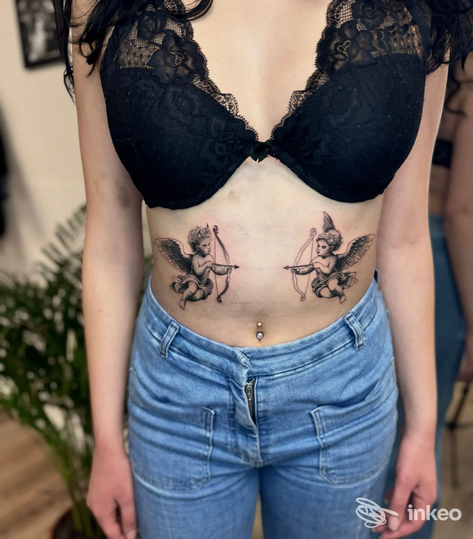 Due tatuaggi speculari di putti con arco sul basso sterno, foto scattata in studio Esseink TATUAGGI E PIERCING, Ivrea.