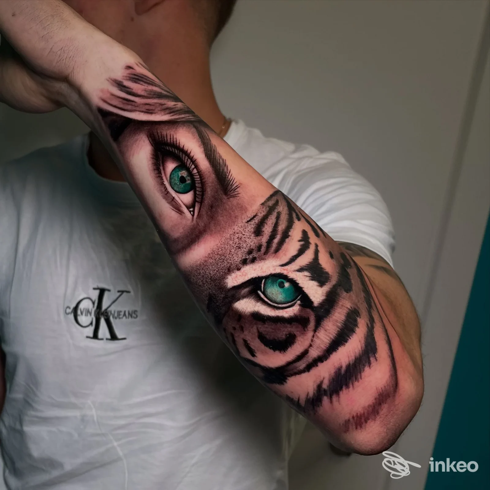 Tatuaggio realistico su avambraccio con occhio umano verde e muso di tigre, foto per Fishbone Tattoo studio a Chieri.