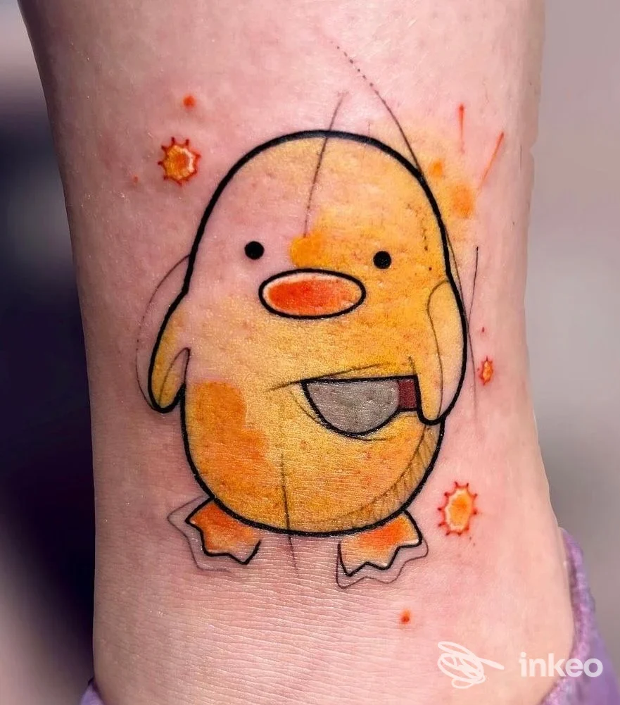 Tatuaggio colorato di un pulcino stilizzato sulla caviglia, realizzato da GEMINI tattoo studio a Chivasso, dettaglio nitido e colori caldi.