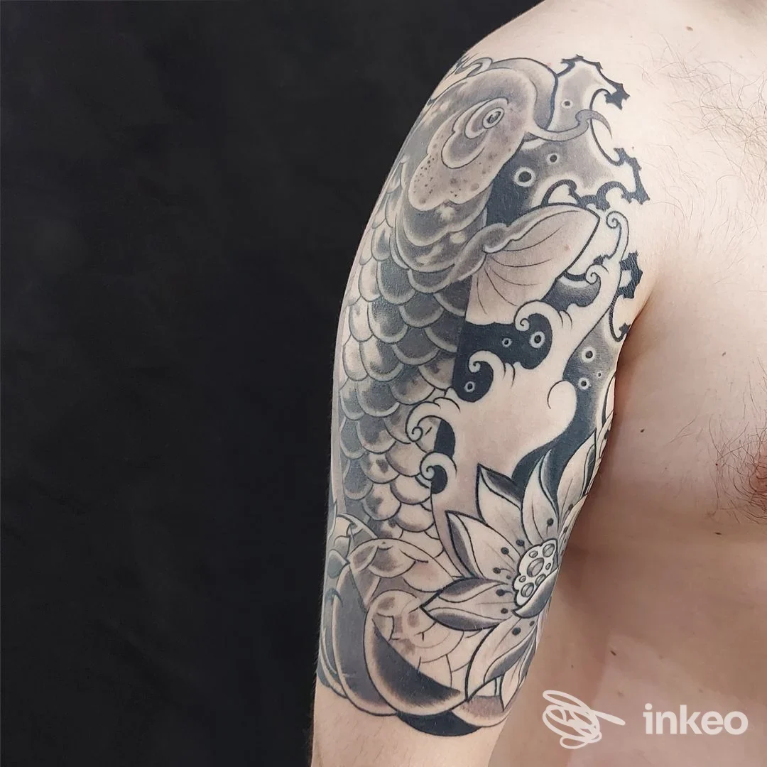 Grande tatuaggio a mezza manica con carpa e fiore sul braccio e sulla spalla, fotografato per Empire Tattoo Studio ad Alpignano.