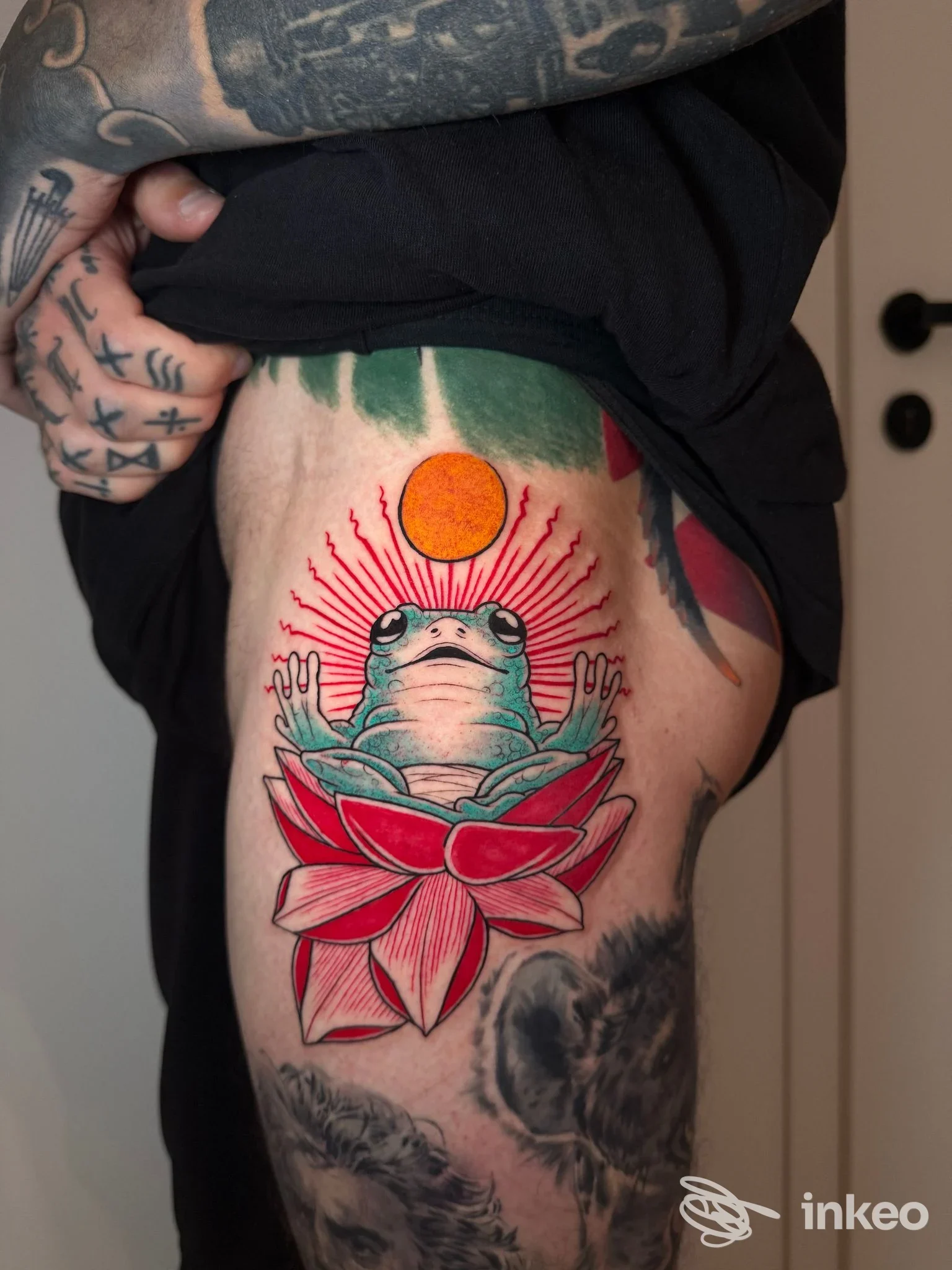 Tatuaggio a colori sulla coscia con rana su fiore di loto e sole, foto realizzata per Fuori Luogo Tattoo Pmu Trucco Semipermanente Piercing ad Alpignano.