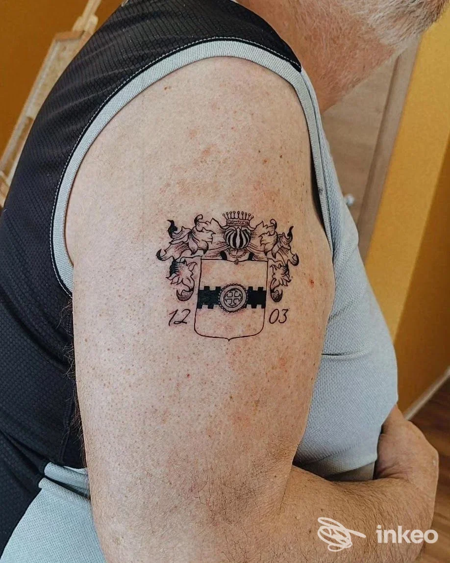 Tatuaggio a stemma in nero sul bicipite di un uomo: foto realizzata presso Horus tattoo e piercing di Riccardo Ragusano, Borgone Susa.