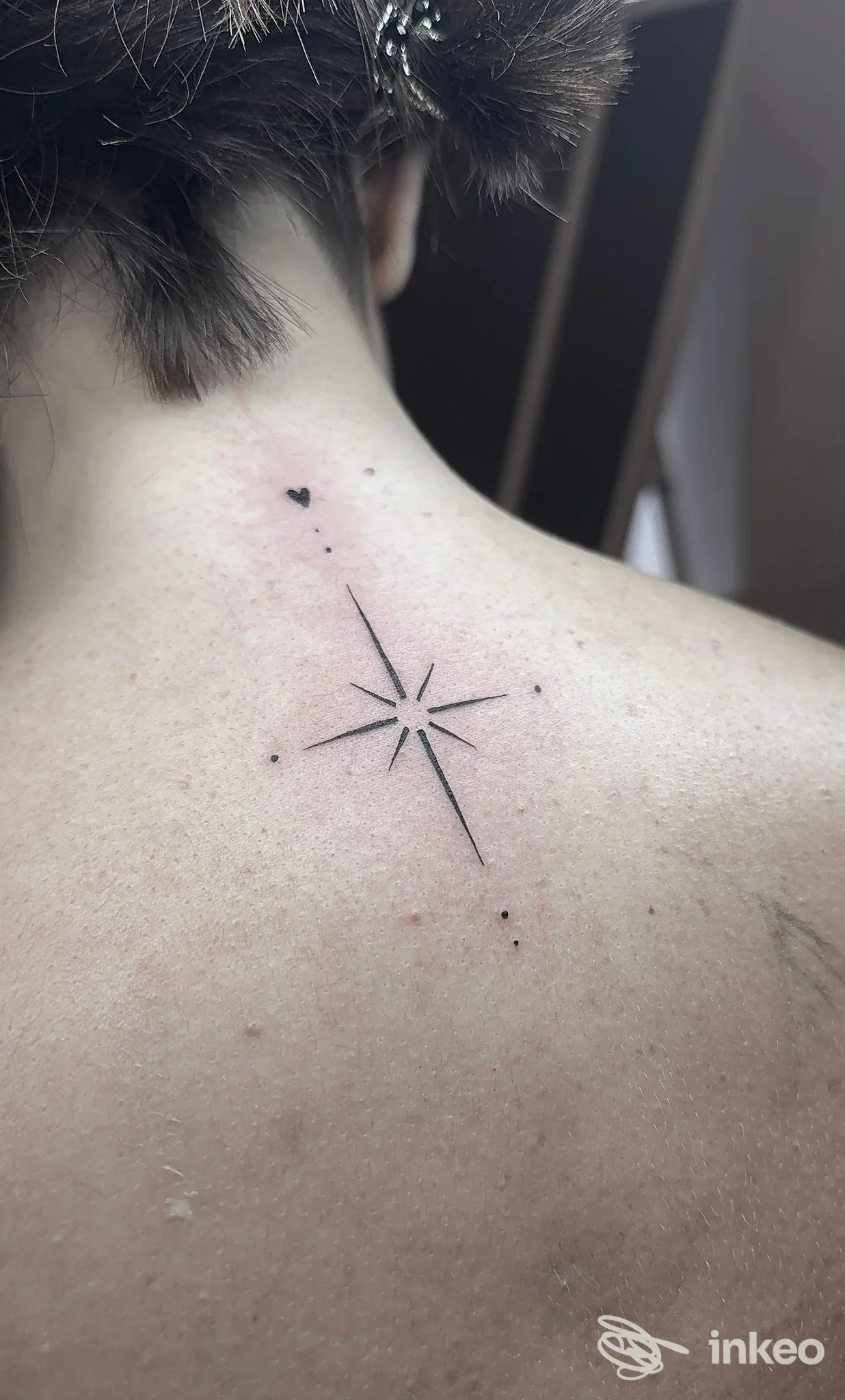 Piccolo tatuaggio a linee nere a forma di stella sulla parte alta della schiena, foto fornita da INK FOR LIFE Tattoo & Piercing Studio, Torino.