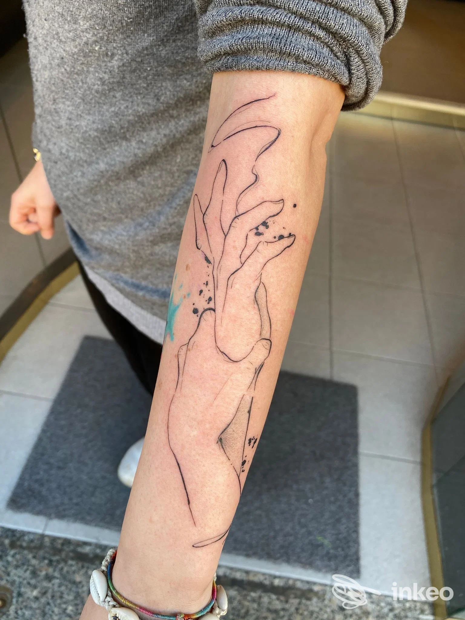 Tatuaggio lineare di mani sull'avambraccio, foto fornita da INK FOR LIFE Tattoo & Piercing Studio, Torino.