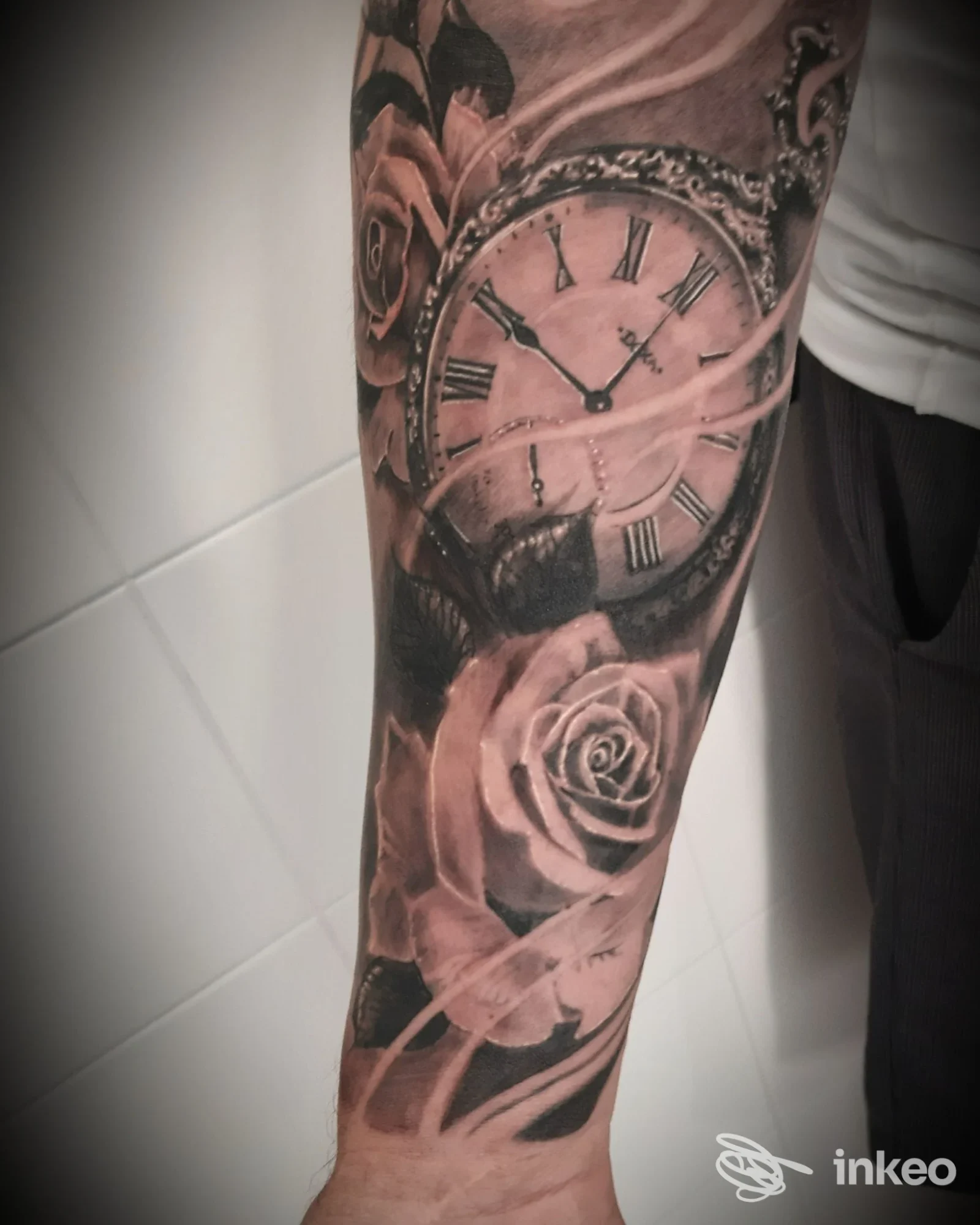 Primo piano di avambraccio tatuato con orologio da tasca e rose, opera presentata da Greg tattoo Art studio, Omegna.