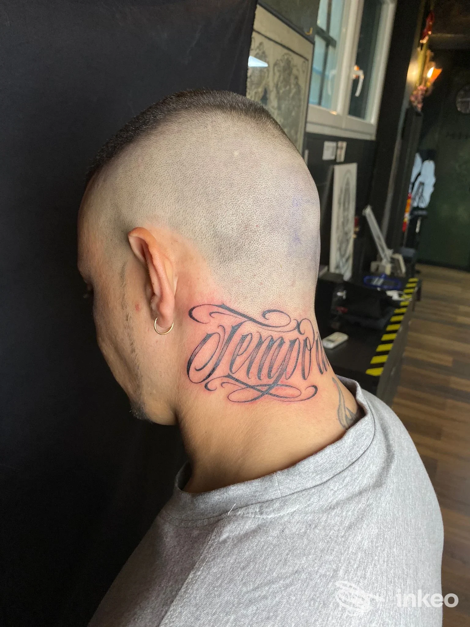 Tatuaggio lettering sul collo di una persona fotografata in Imago Amens Tattoo Studio a Torino, sguardo sul lato/nuca.