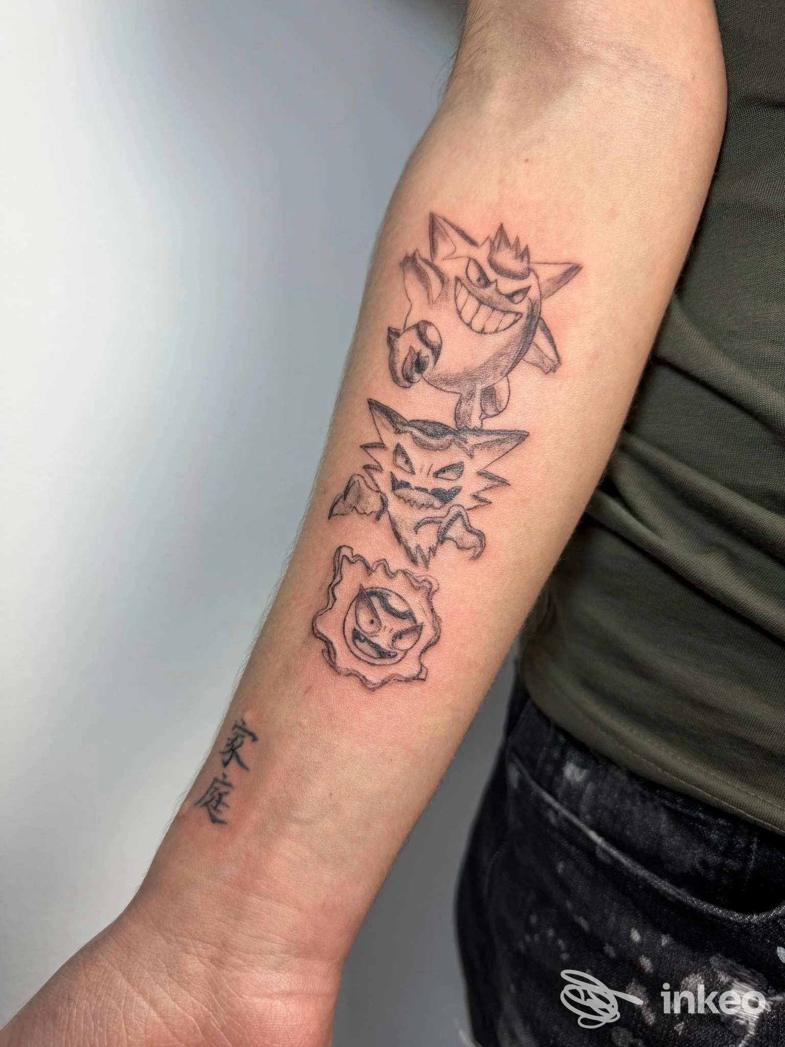 Avambraccio tatuato con tre volti stilizzati in nero, foto di Inkoscienza Studio Tattoo, Torino.