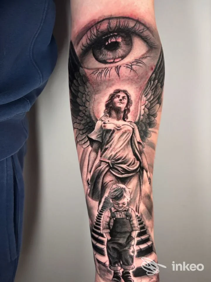 Tatuaggio realistico in bianco e nero su avambraccio con occhio, angelo e bambino; immagine fornita da Il Camaleonte Tatoo & Piercing, Torino.