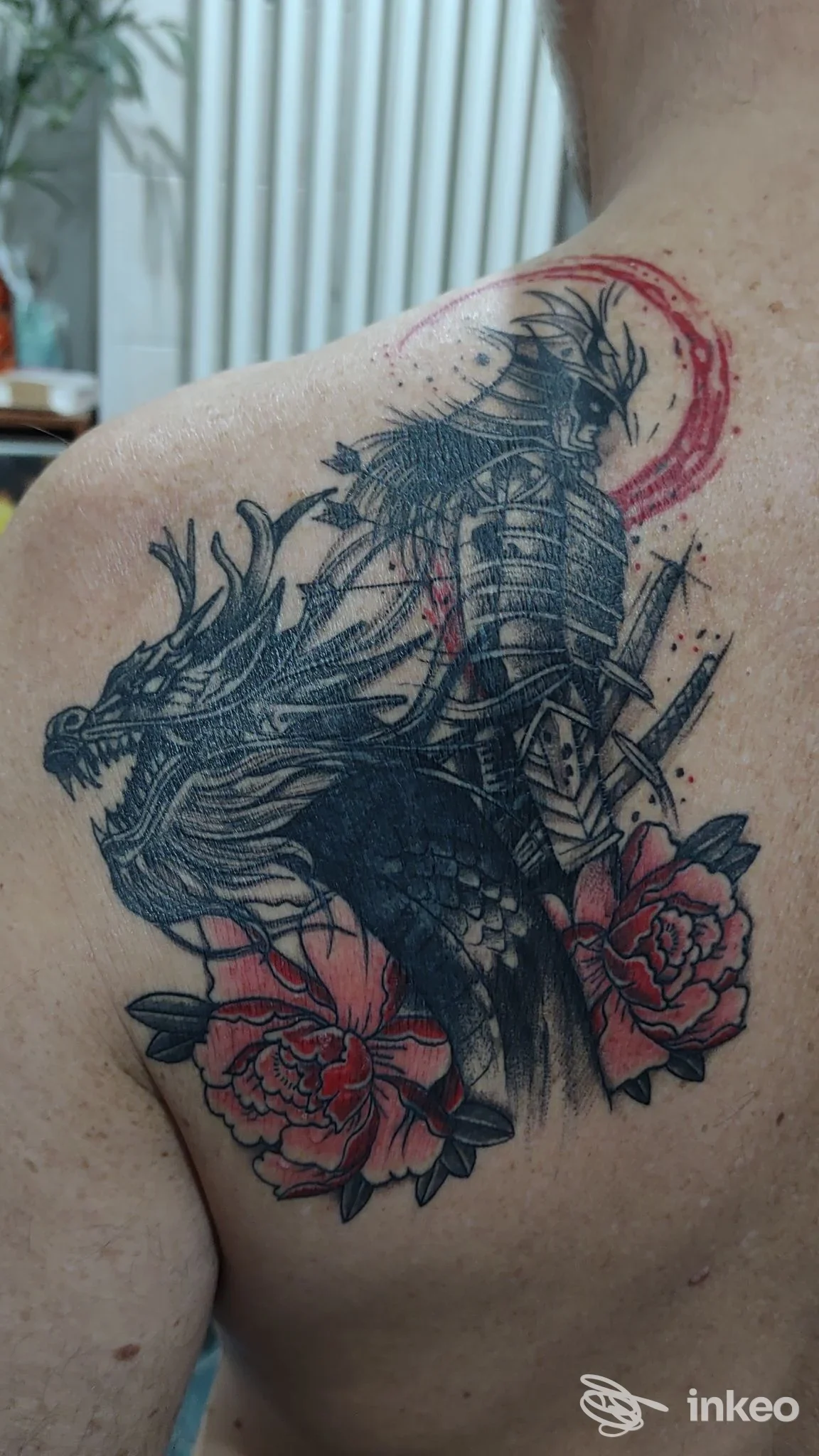 Grande tatuaggio sulla spalla e parte alta della schiena, con figura di guerriero e dettagli rossi. Inkredibile Tattoo Studio, Arona.