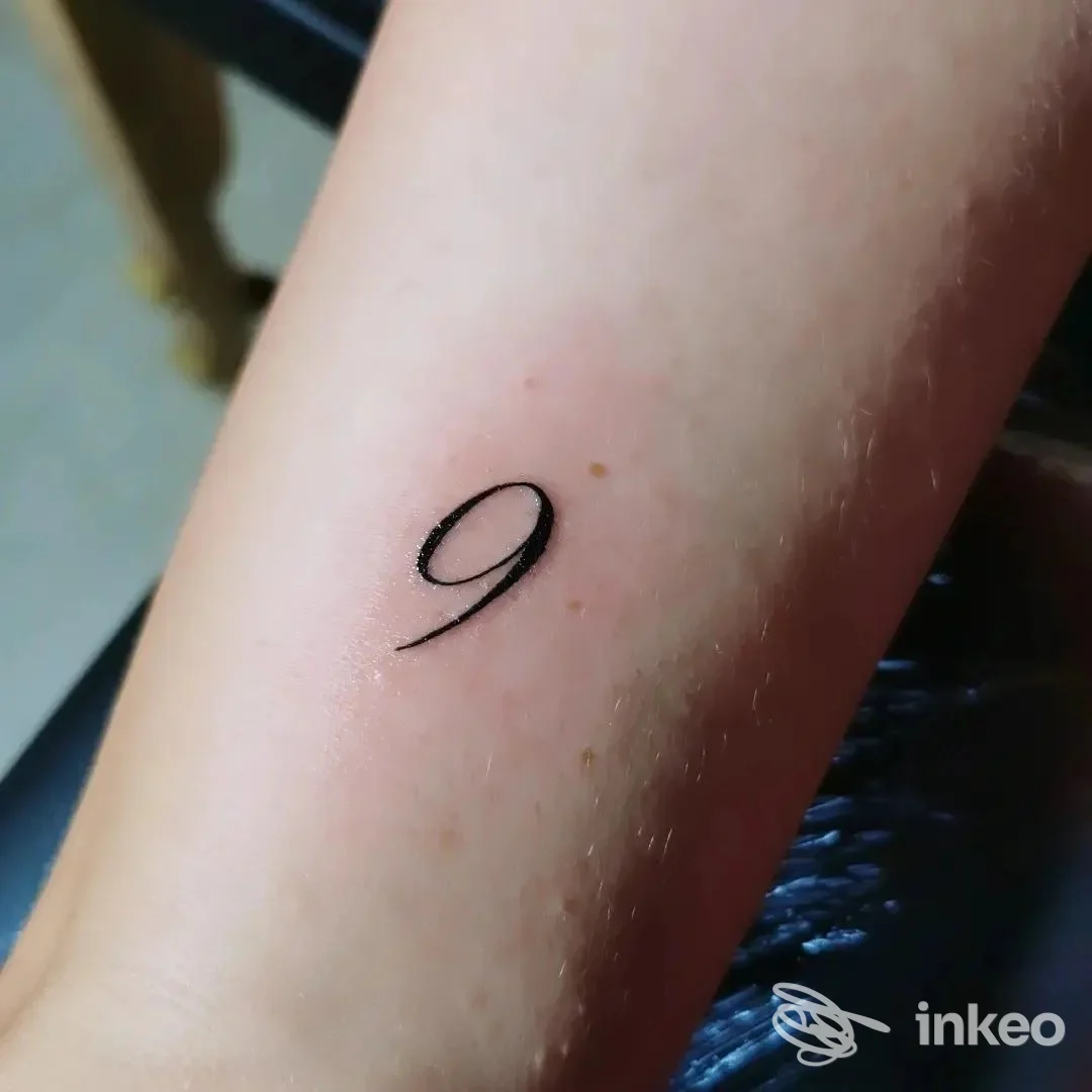 Piccolo tatuaggio minimal a forma di '9' sull'avambraccio interno, foto scattata in studio KINK tattoo studio a Biella.