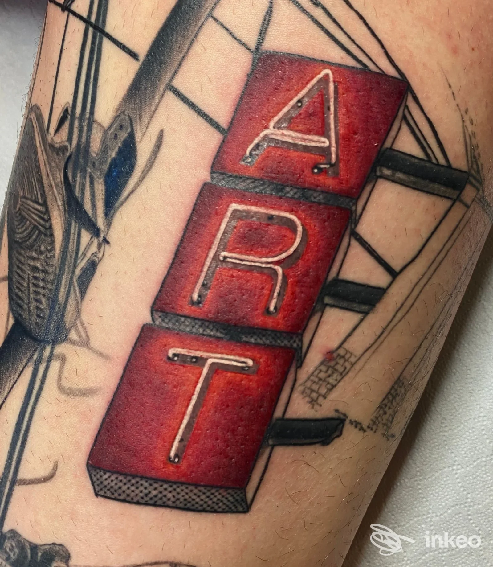 Primo piano di un tatuaggio a blocchi rossi con lettere in rilievo sull'avambraccio. Kalavera Tattoo Studio, Settimo Torinese.