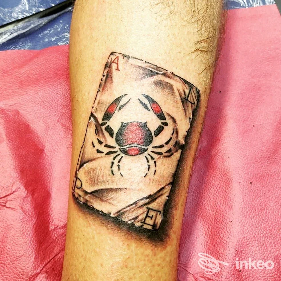 Tatuaggio su polpaccio raffigurante una carta da gioco con un ragno, eseguito da LA VALLE DI LACRIME TATTOO a Buttigliera Alta.