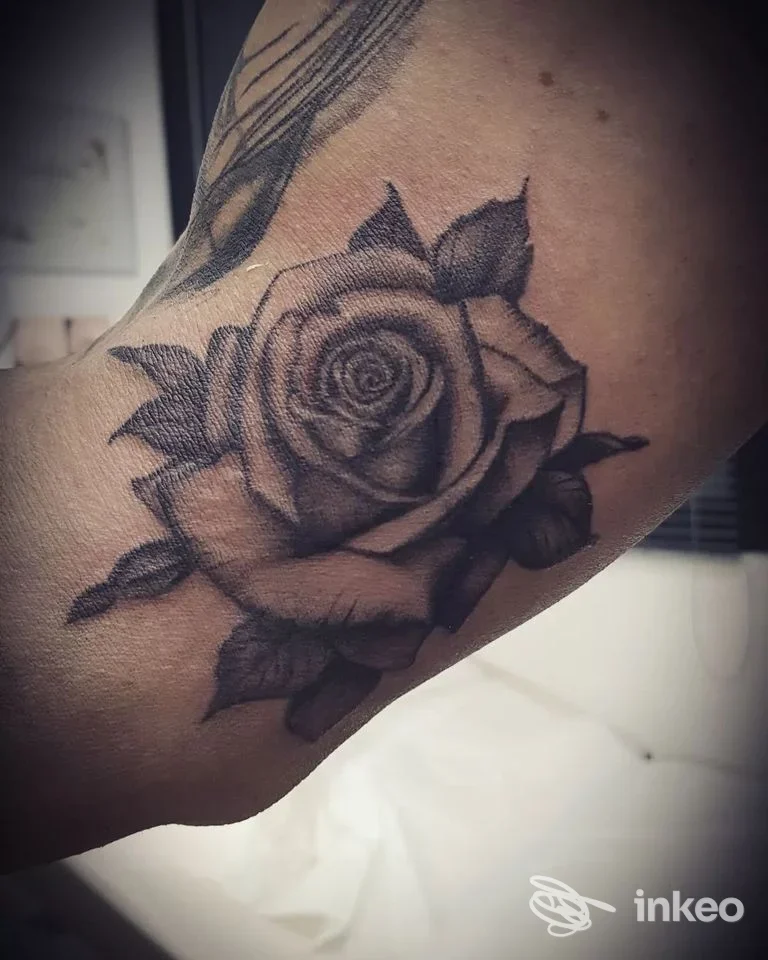 Tatuaggio realistico in nero e grigio di una rosa sull'interno braccio, fotografato nello studio Lady Tattoo a Novara.