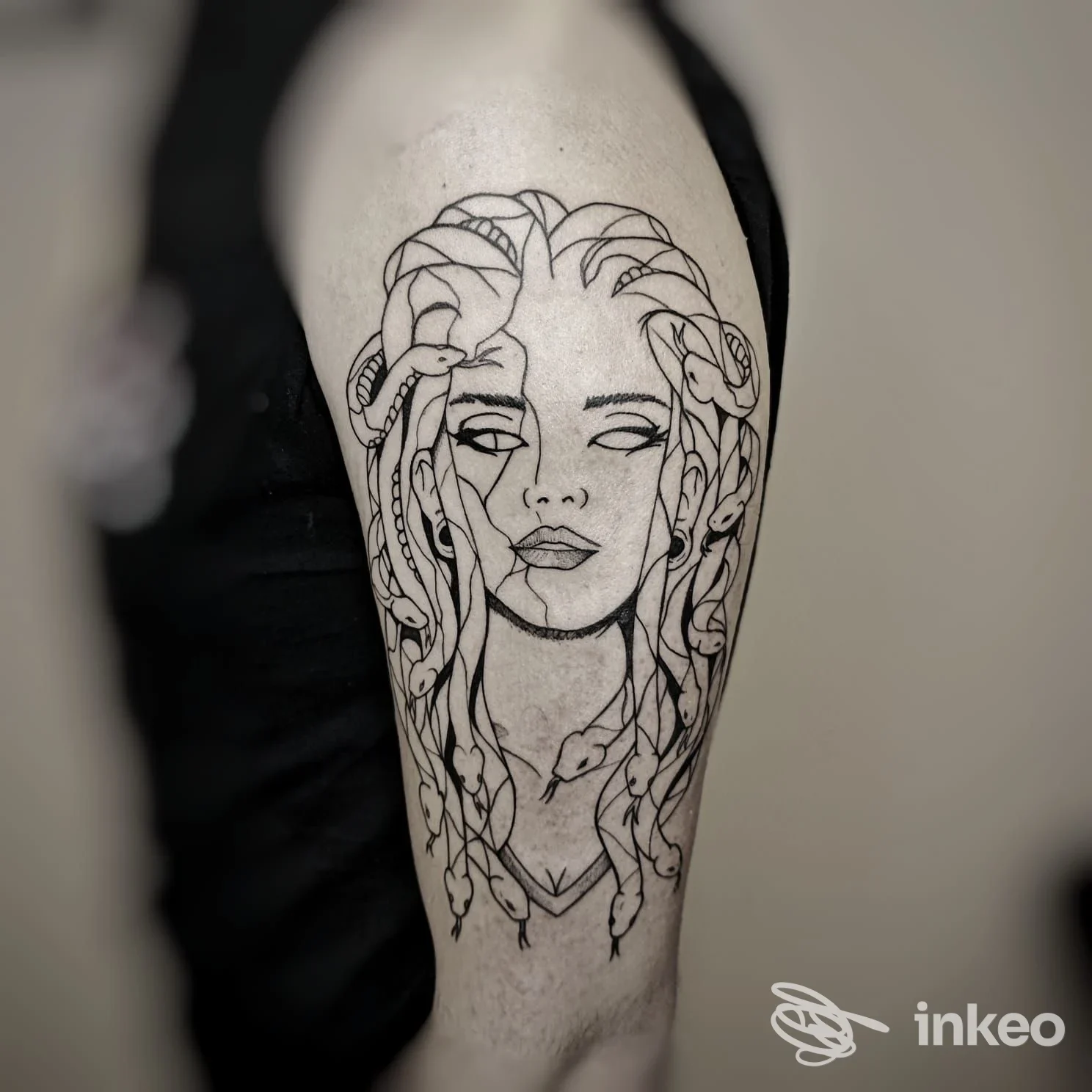 Tatuaggio in linework su braccio superiore con volto femminile stilizzato, realizzato da M.R. TATTOO STUDIO CANELLI a Canelli.