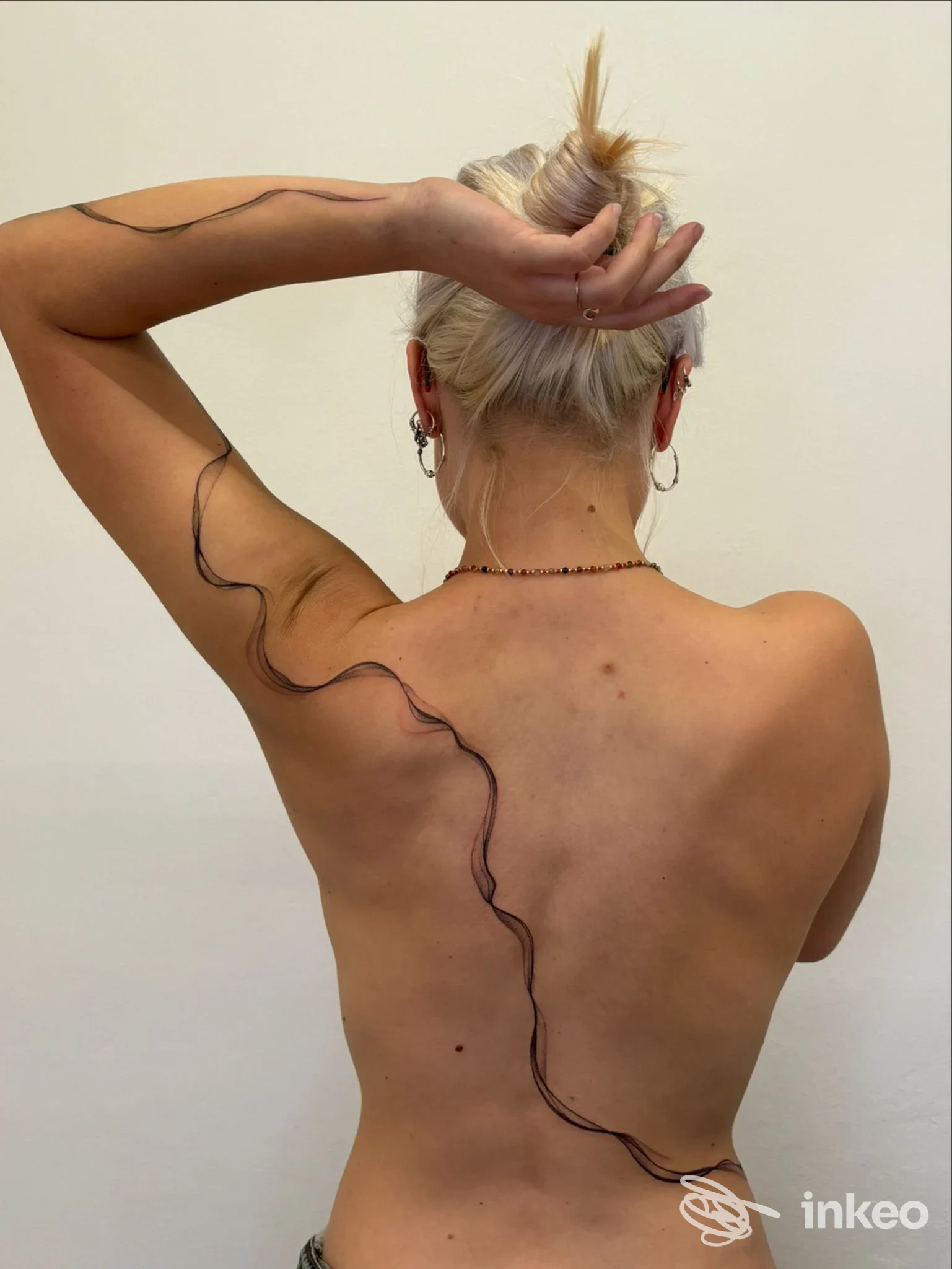 Vista posteriore di una schiena con tatuaggio lineare lungo scapola e fianco, foto da MAY tattoo atelier, Torino.