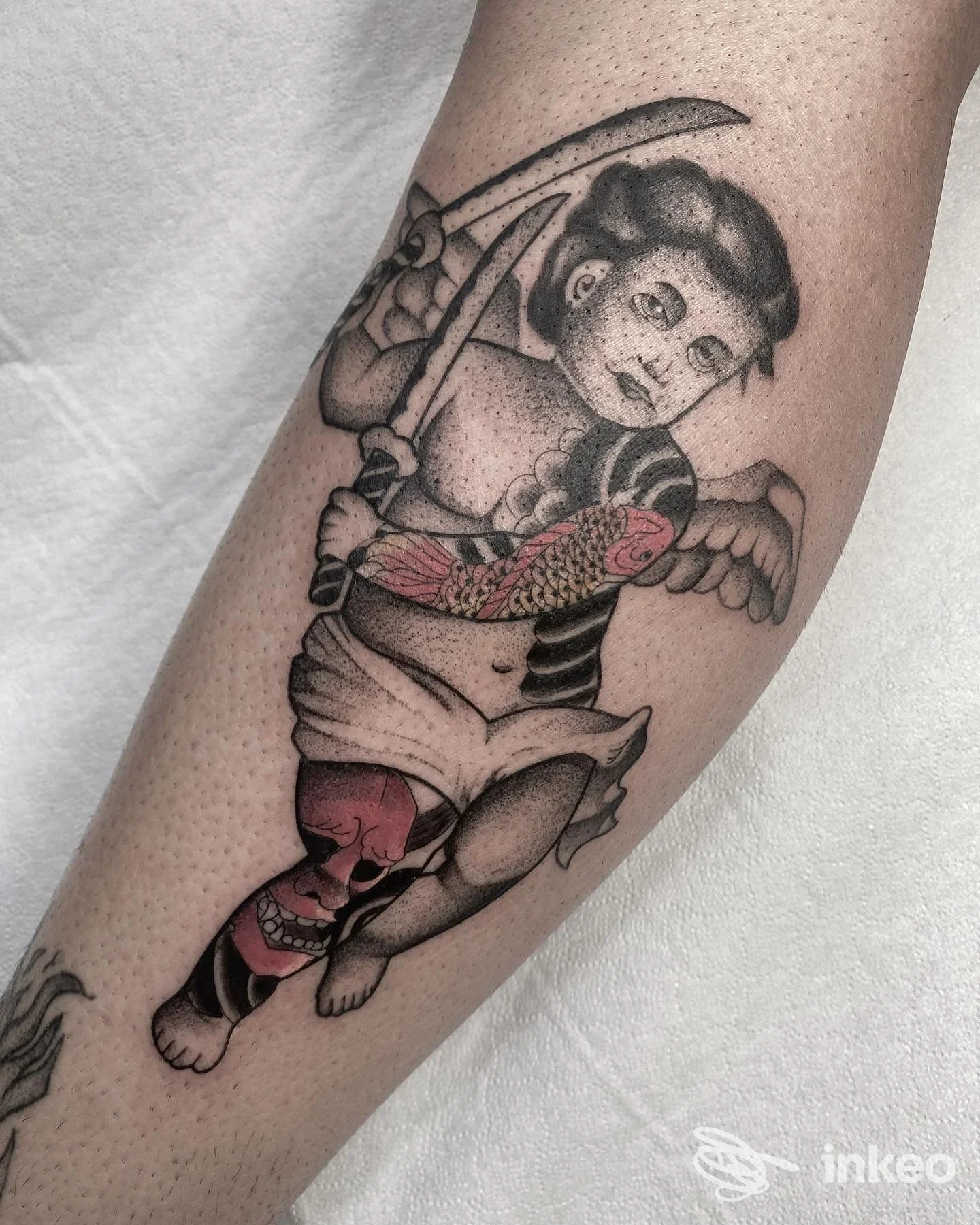 Tatuaggio su polpaccio raffigurante un cherubino armato con lame e dettagli koi sul braccio, realizzato da NOBS TATTOO CLUB a Torino.