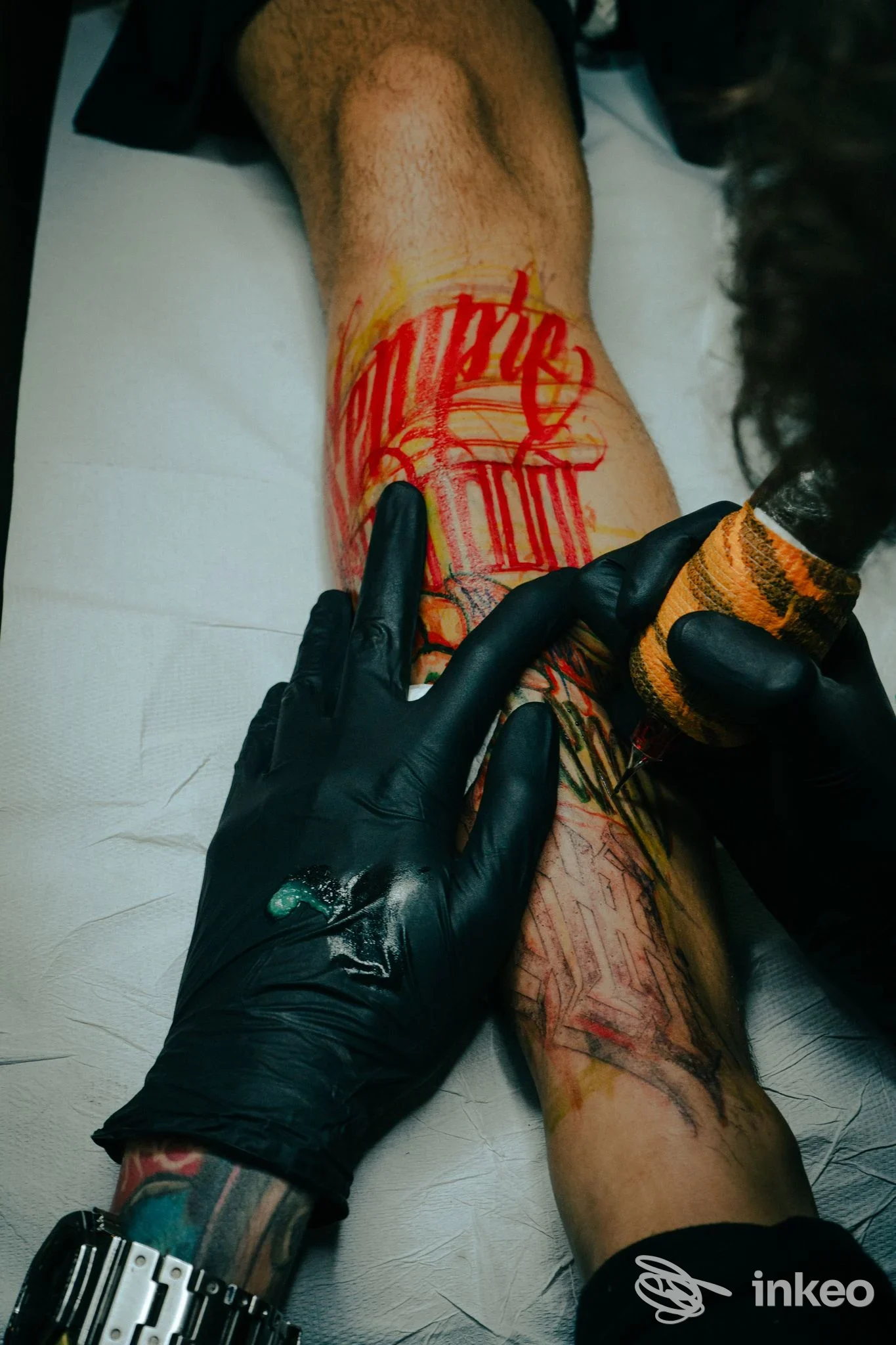 Tatuaggio in corso sull’avambraccio con mani guantate dell’artista, foto fornita da NOBS TATTOO CLUB, Torino.