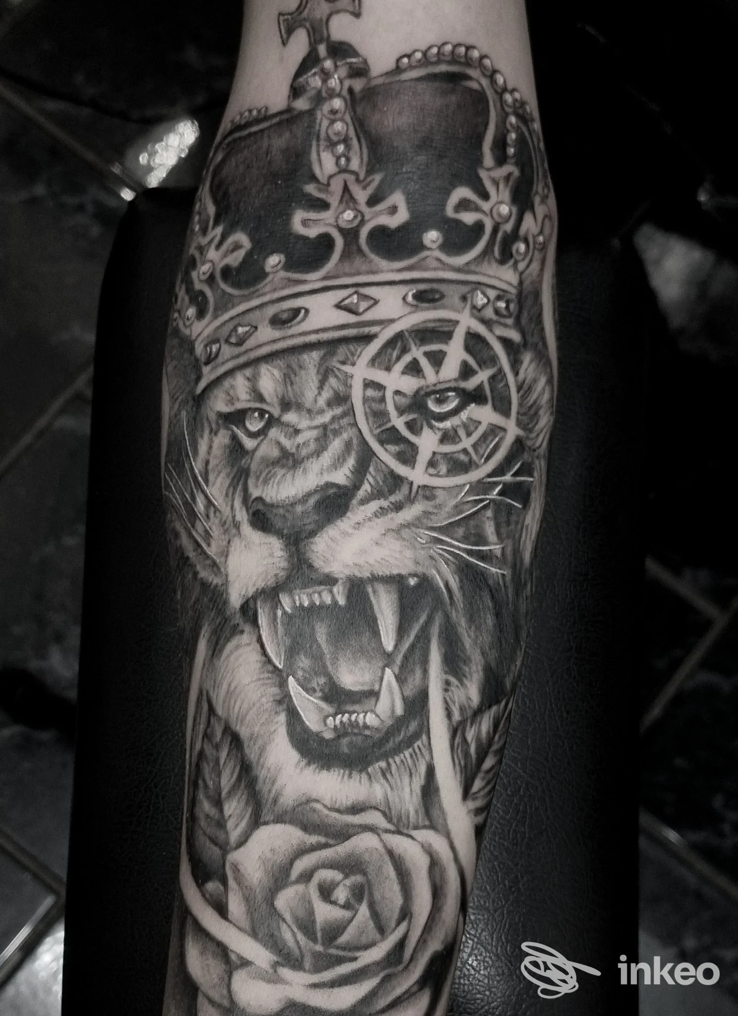 Tatuaggio realistico in bianco e nero su avambraccio: leone con corona e rosa — Nivida Tattoo, Torino.