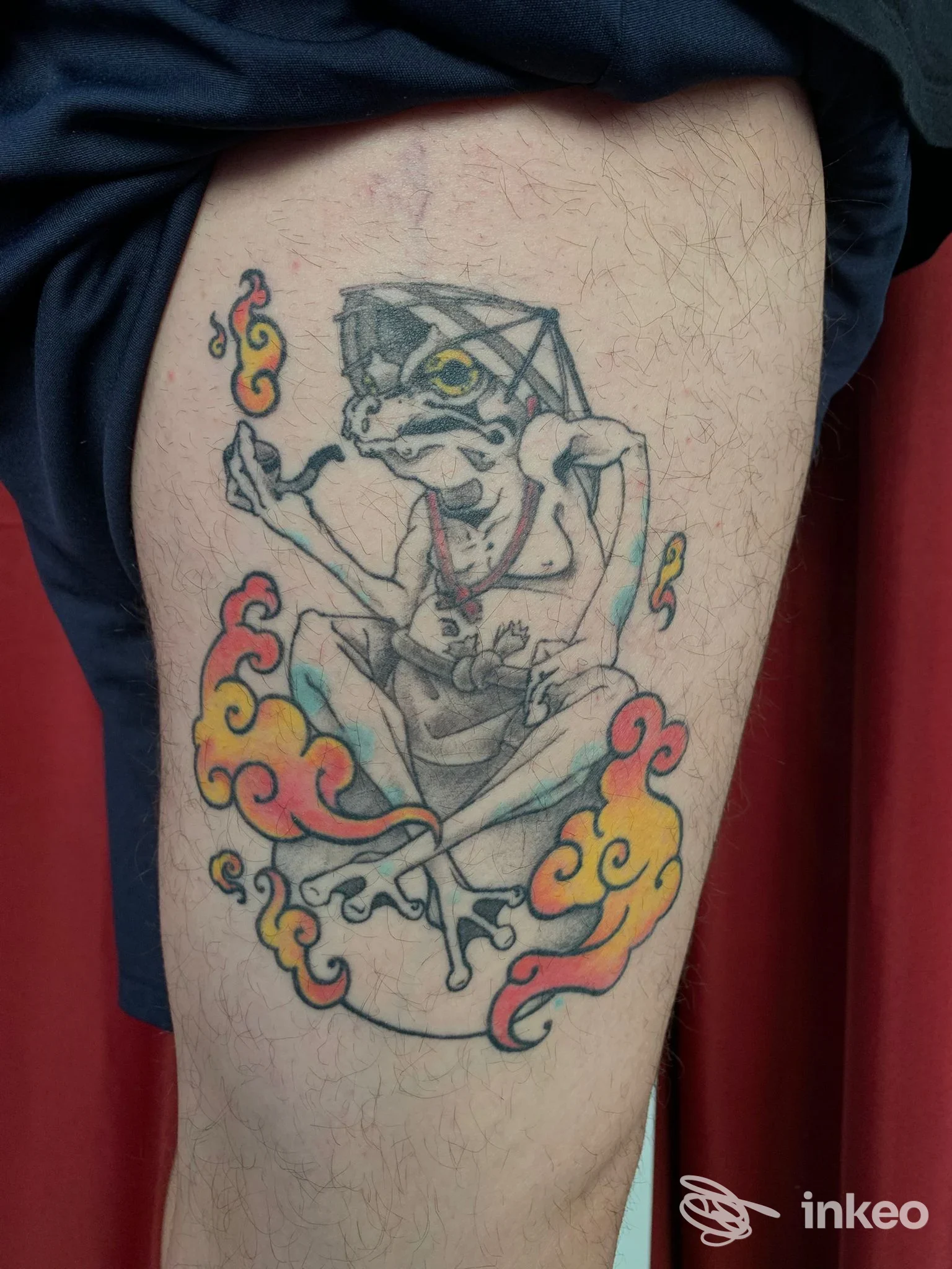Tatuaggio sulla coscia raffigurante una rana meditante con nuvole colorate, foto di Odd | Tattoo & Piercing, Torino.