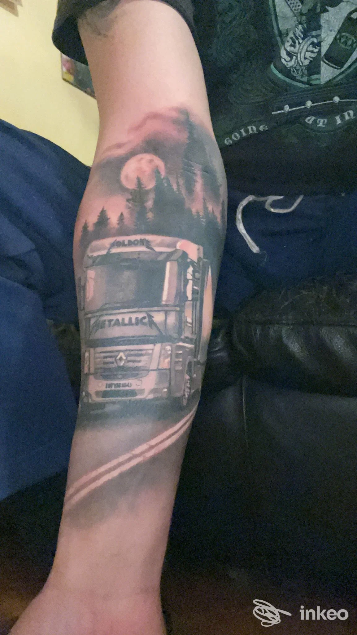 Avambraccio tatuato con un camion realistico, strada e foresta sotto una luna piena; lavoro fotografato di OviTattoo Art, Torino.