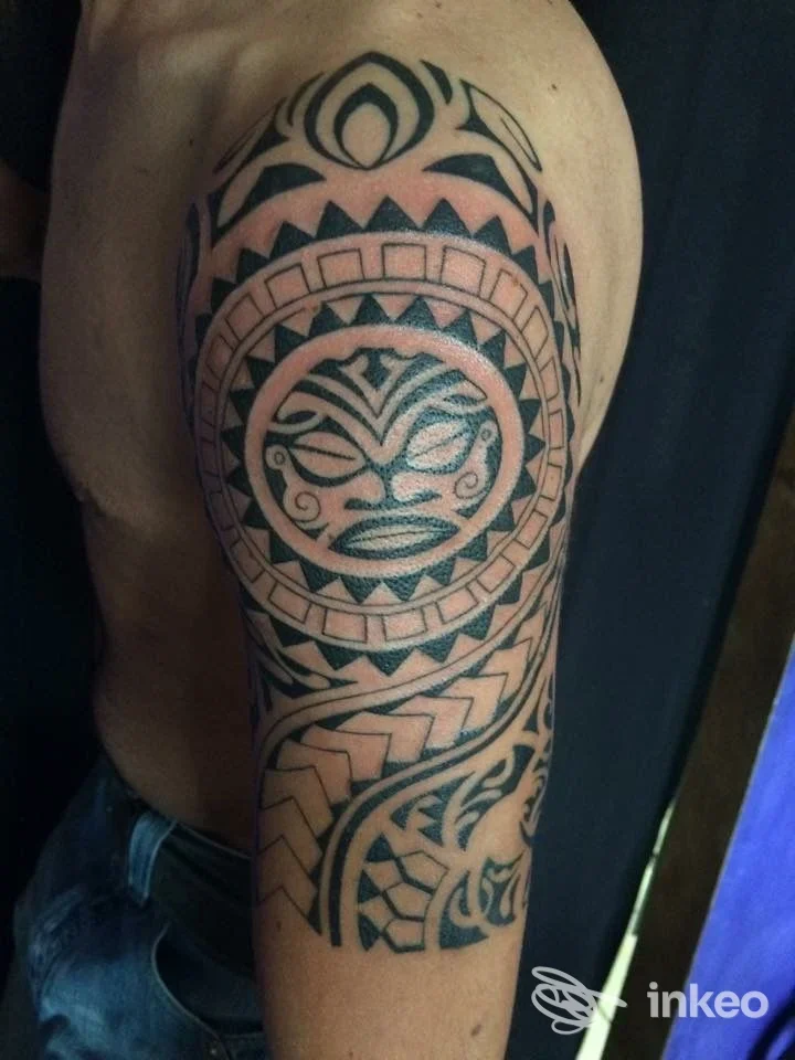 Tatuaggio tribale nero esteso su spalla e braccio superiore di una persona, realizzato da Pischy Tattoo a Torino, vista laterale.
