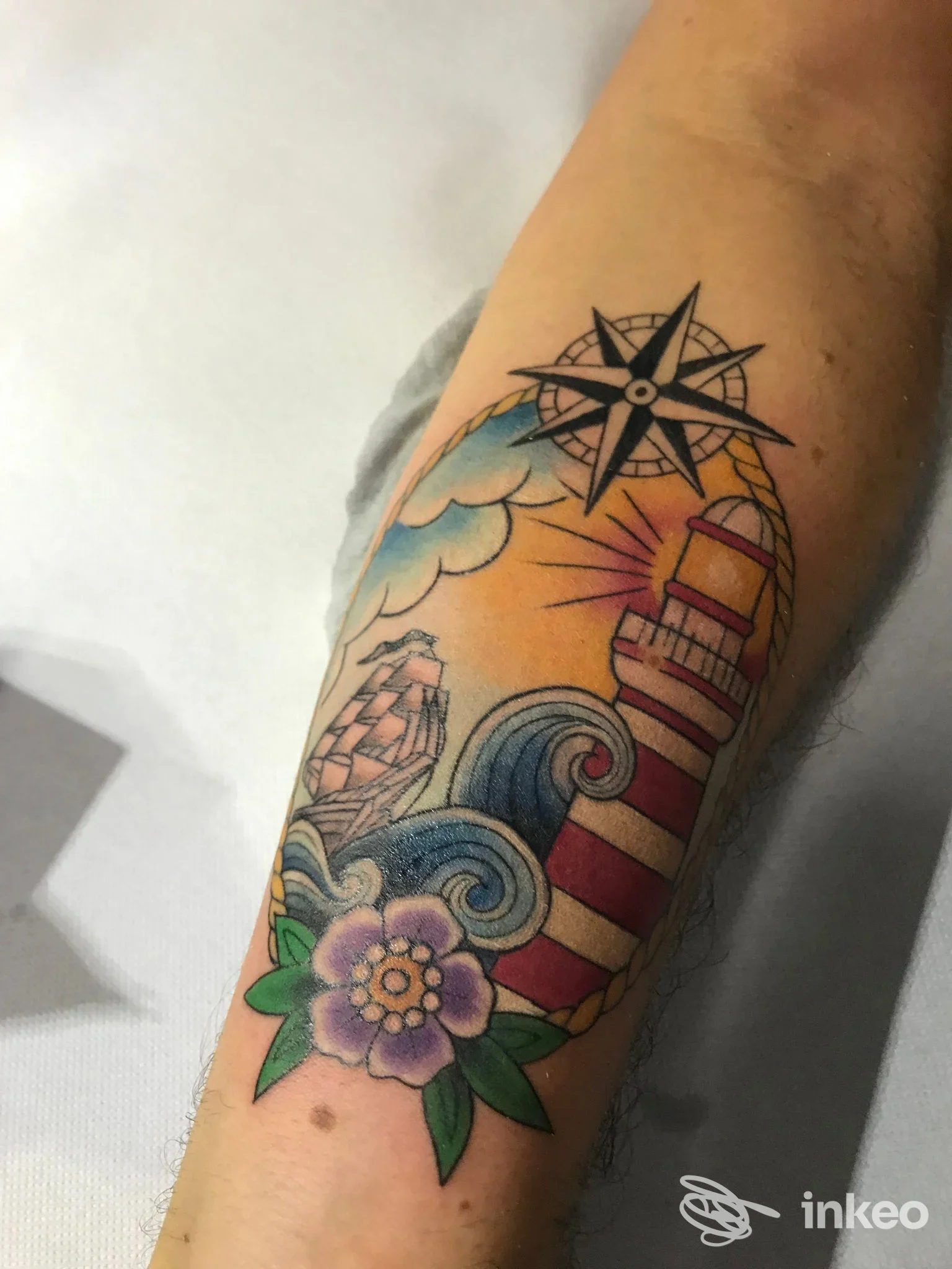 Tatuaggio marinaro a colori sull'avambraccio raffigurante faro, nave, bussola e fiore, Pischy Tattoo, Torino.