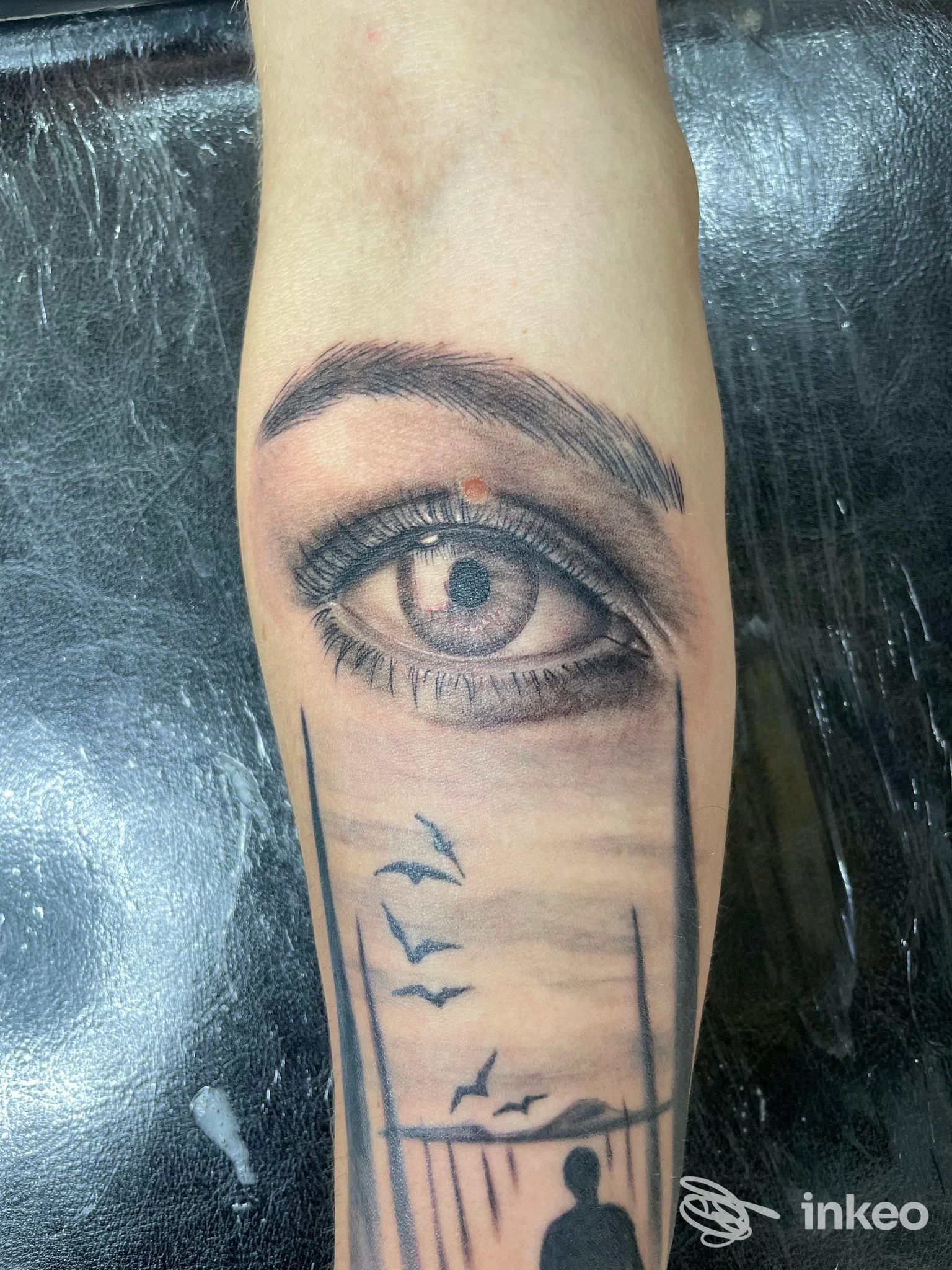 Tatuaggio realistico di un occhio e paesaggio sull'avambraccio, foto dallo studio PrimusArt Tattoo a Vercelli.