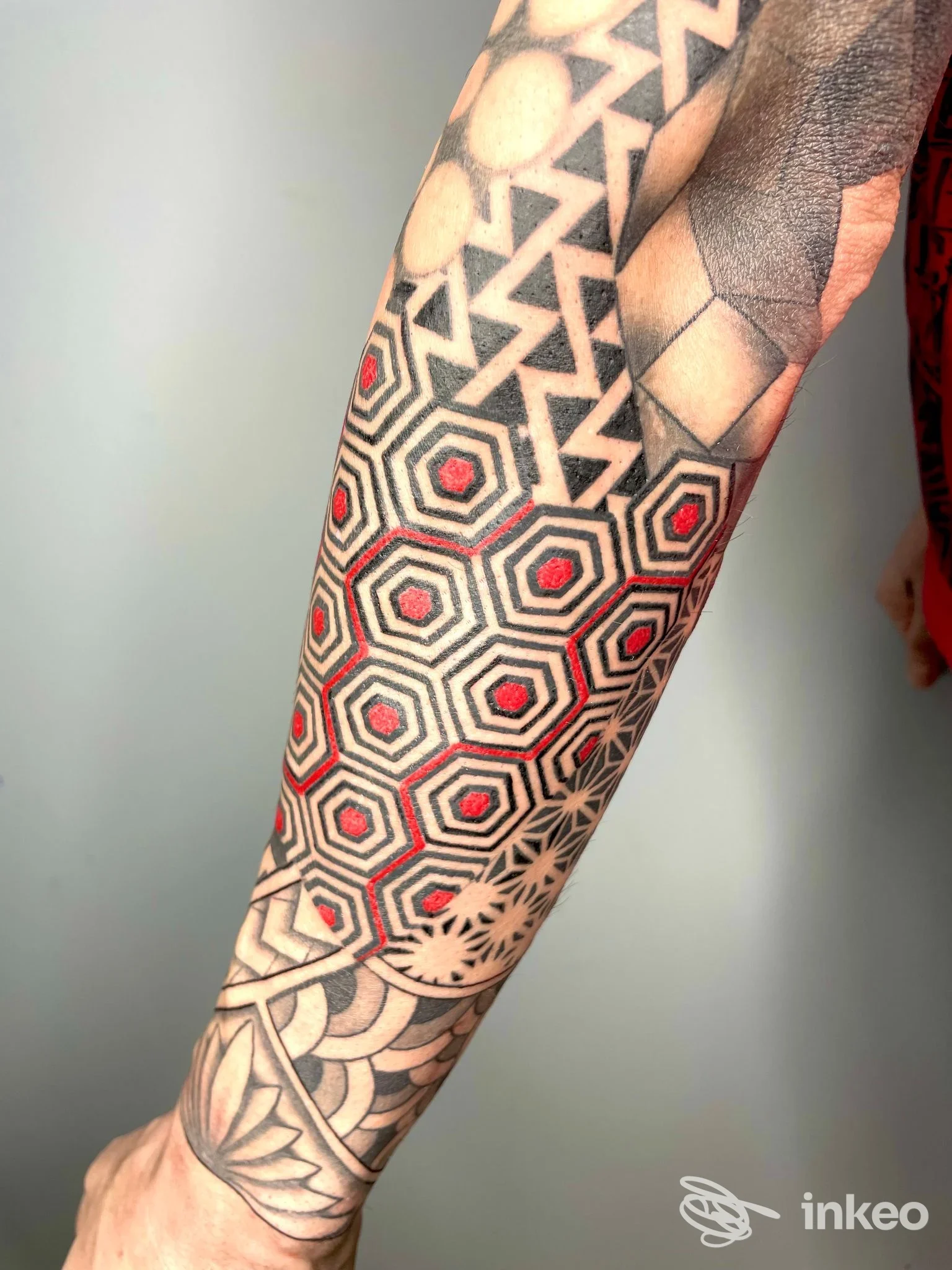 Avambraccio con tatuaggio geometrico nero e rosso, dettagli precisi; foto fornita da OTTANT8 studio tattoo, Alessandria.