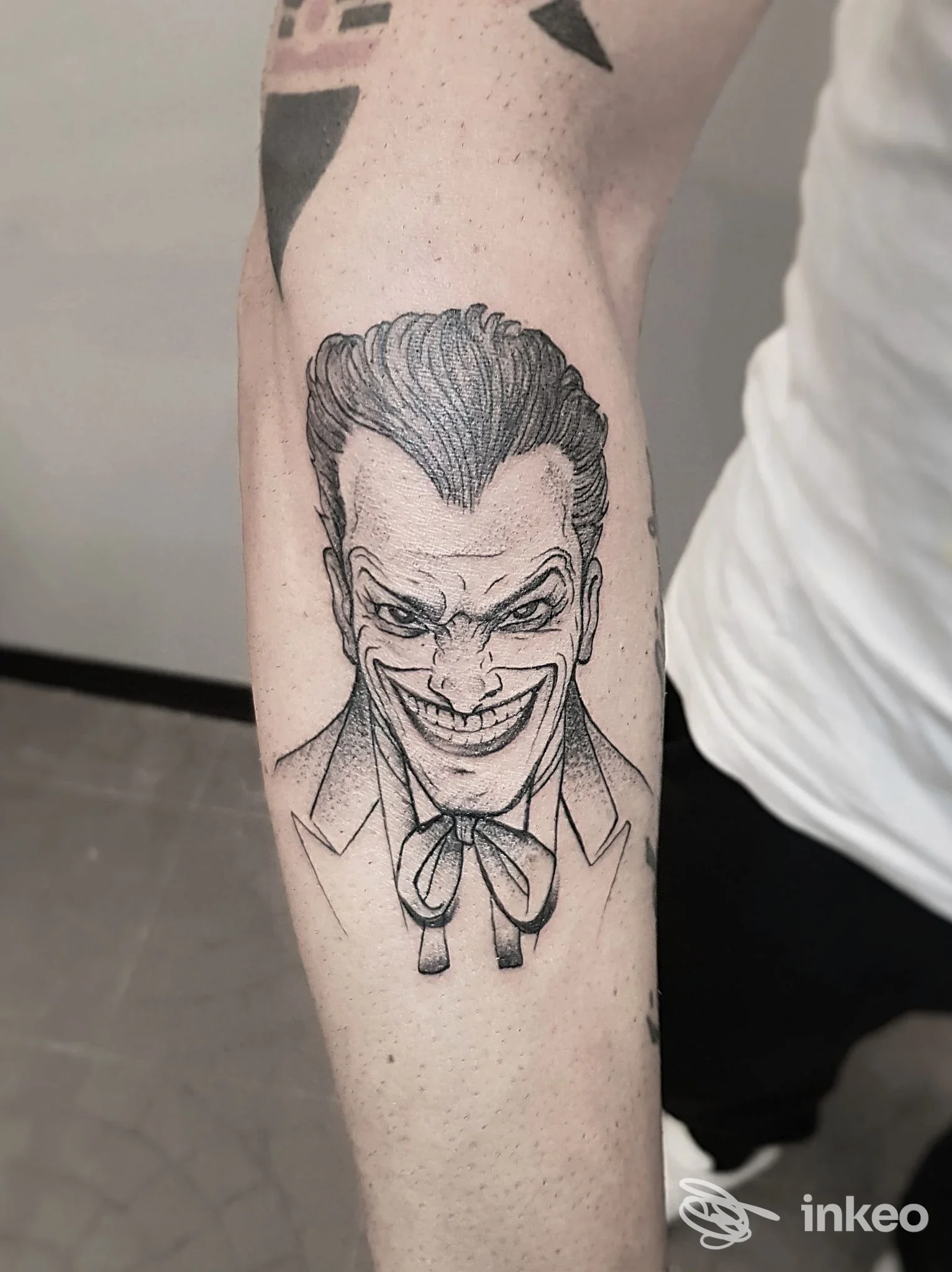 Tatuaggio in bianco e nero sul avambraccio mostrato da Prisma Tattoo Studio, Torino: volto stilizzato con linework e ombreggiature.