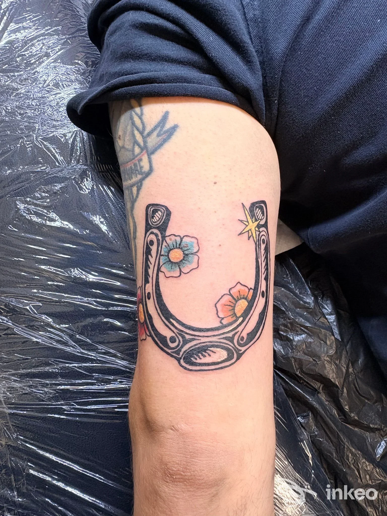 Tatuaggio a ferro di cavallo con fiori colorati sul braccio, realizzato da Ritual Tattoo di Torino.