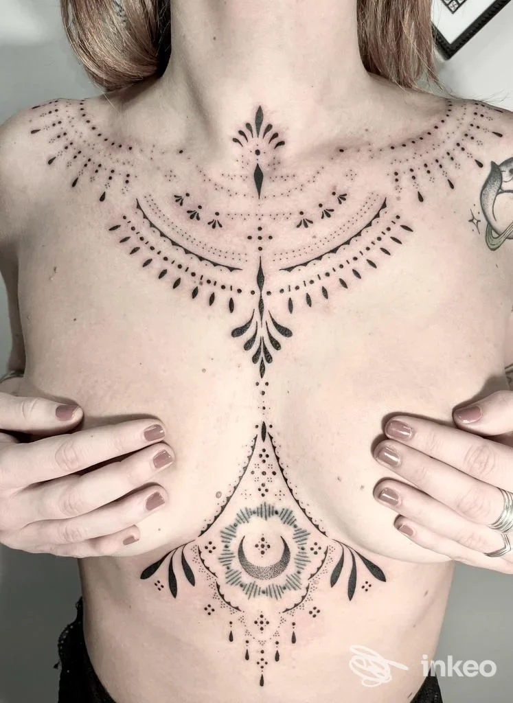 Tatuaggio ornamentale nero sullo sterno e sotto il seno, foto fornita da Shake Tattoo Studio, Domodossola.