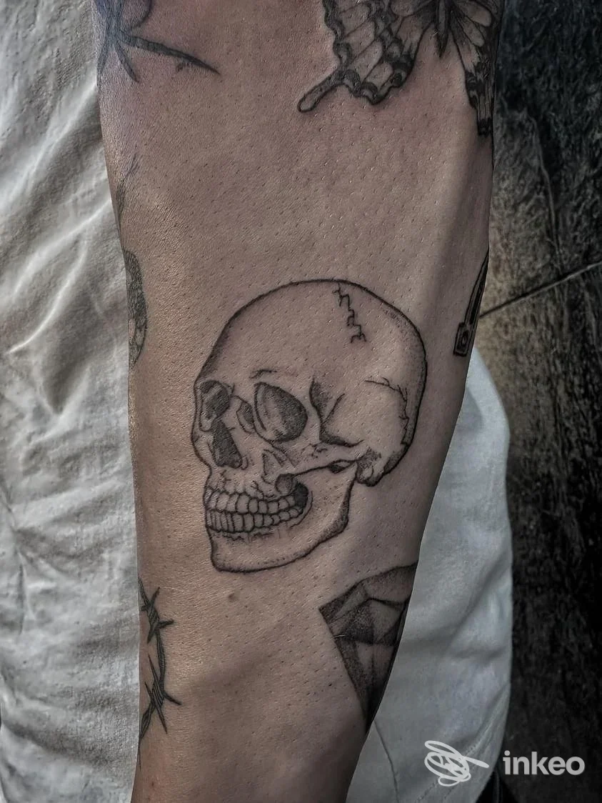 Tatuaggio di un teschio in bianco e nero sull'avambraccio, fotografato per Shake Tattoo Studio a Domodossola.