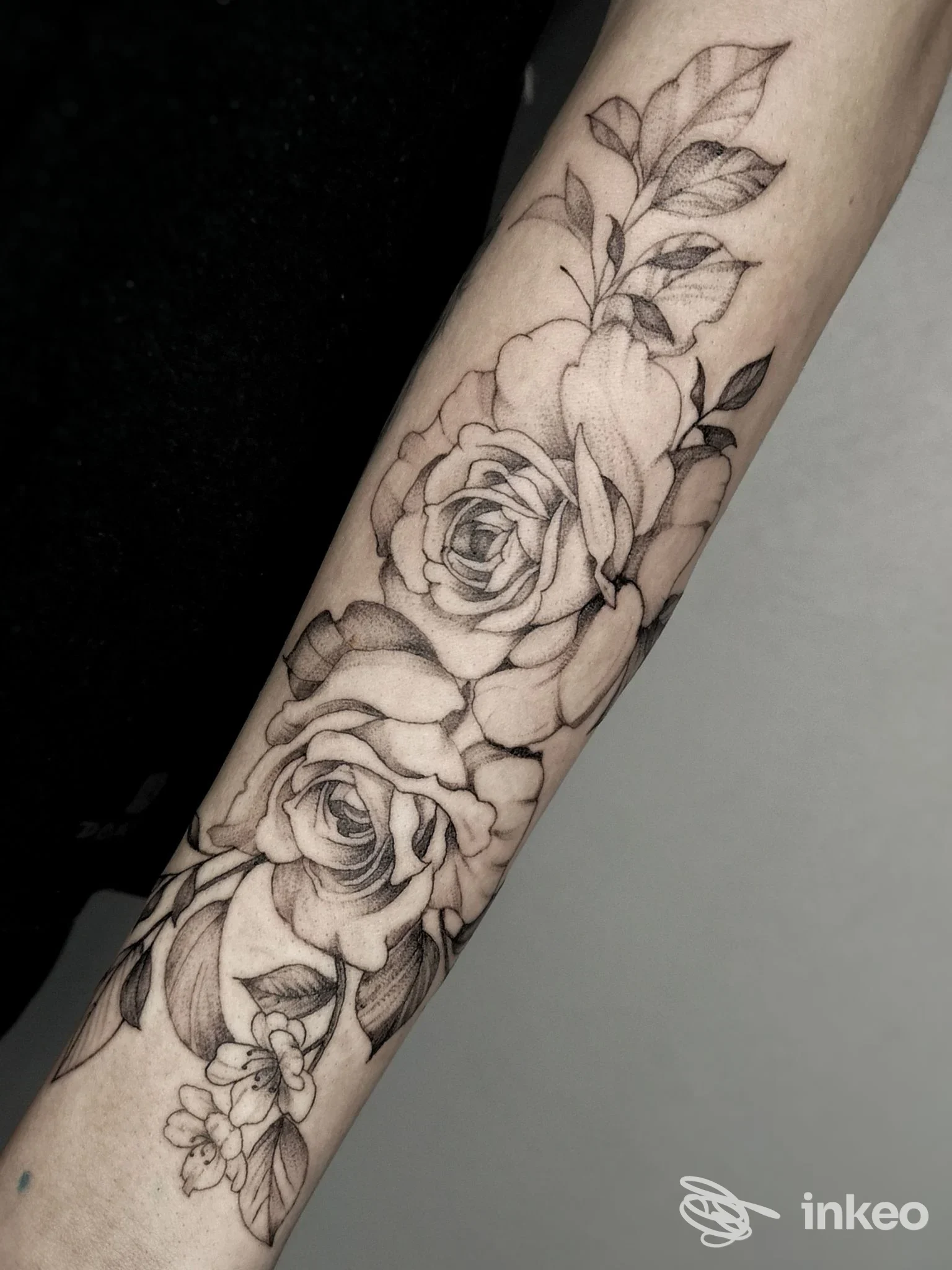 Primo piano di un tatuaggio floreale con rose e foglie sull'avambraccio, realizzato da Shake Tattoo Studio a Domodossola.