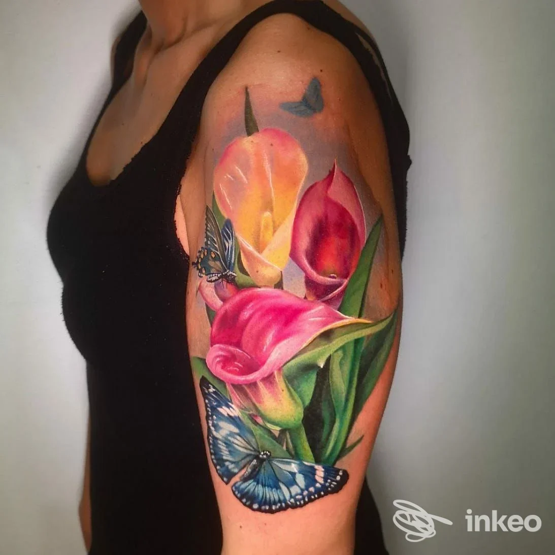 Tatuaggio realistico di calle e farfalle sul braccio superiore, realizzato da STRAY ART TATTOO STUDIO a Borgomanero.