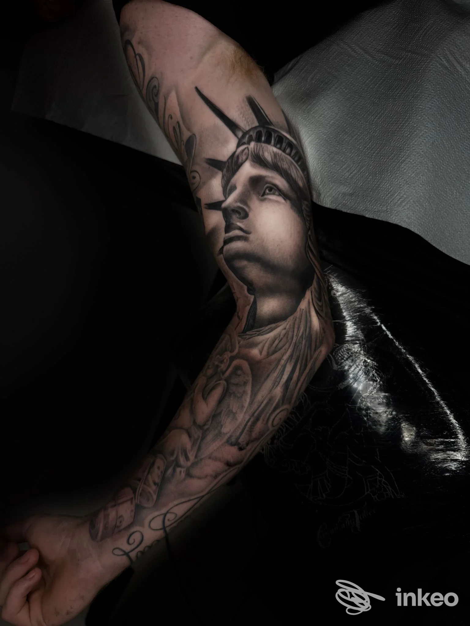 Braccio sinistro con tatuaggio realistico raffigurante la Statua della Libertà, senza overlay o testo visibile. Si distingue chiaramente l’opera sulla pelle.