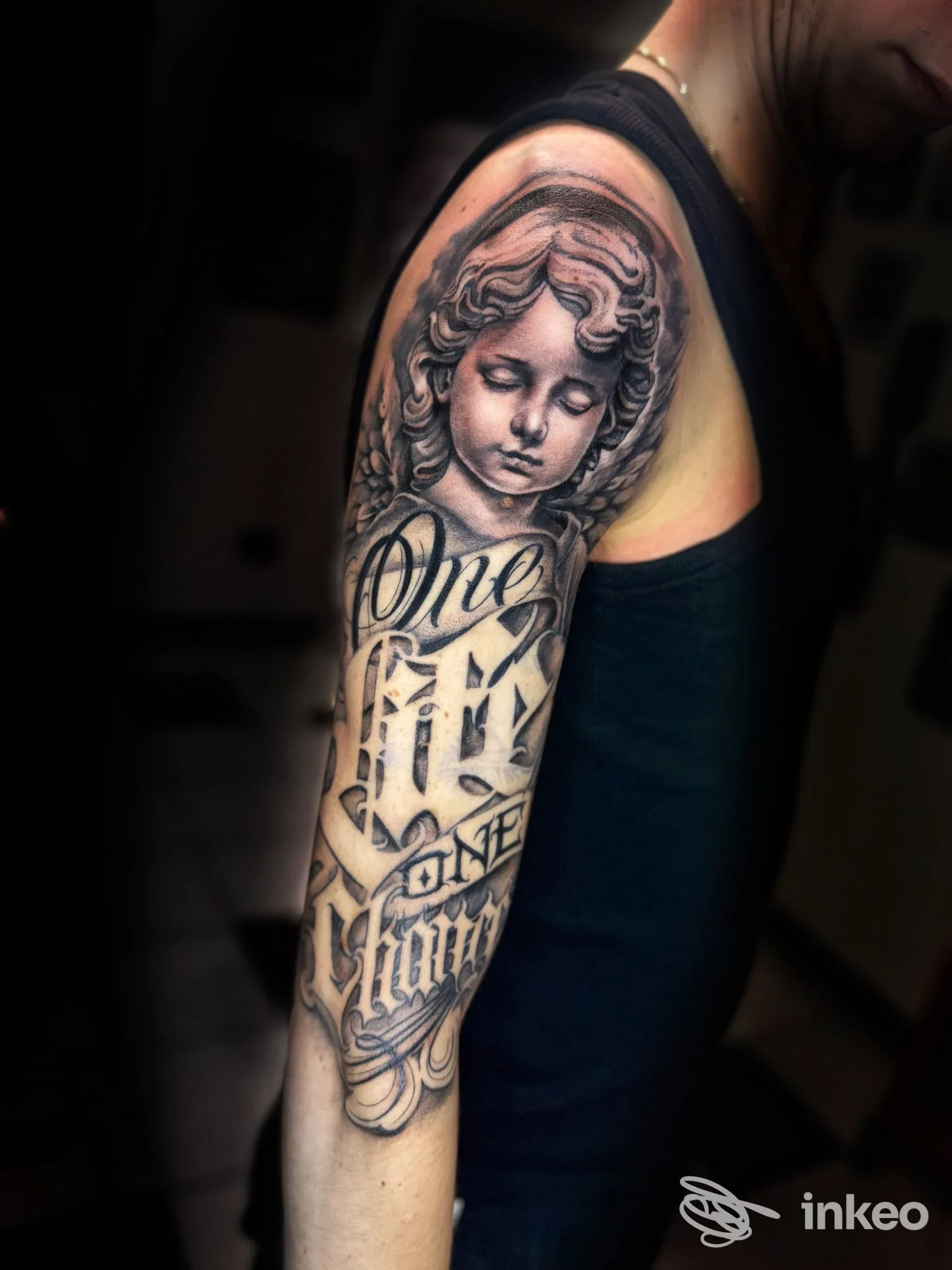 Tattoo sull'avambraccio di una persona, ritratto angelico con scritte decorative nello stile classico.