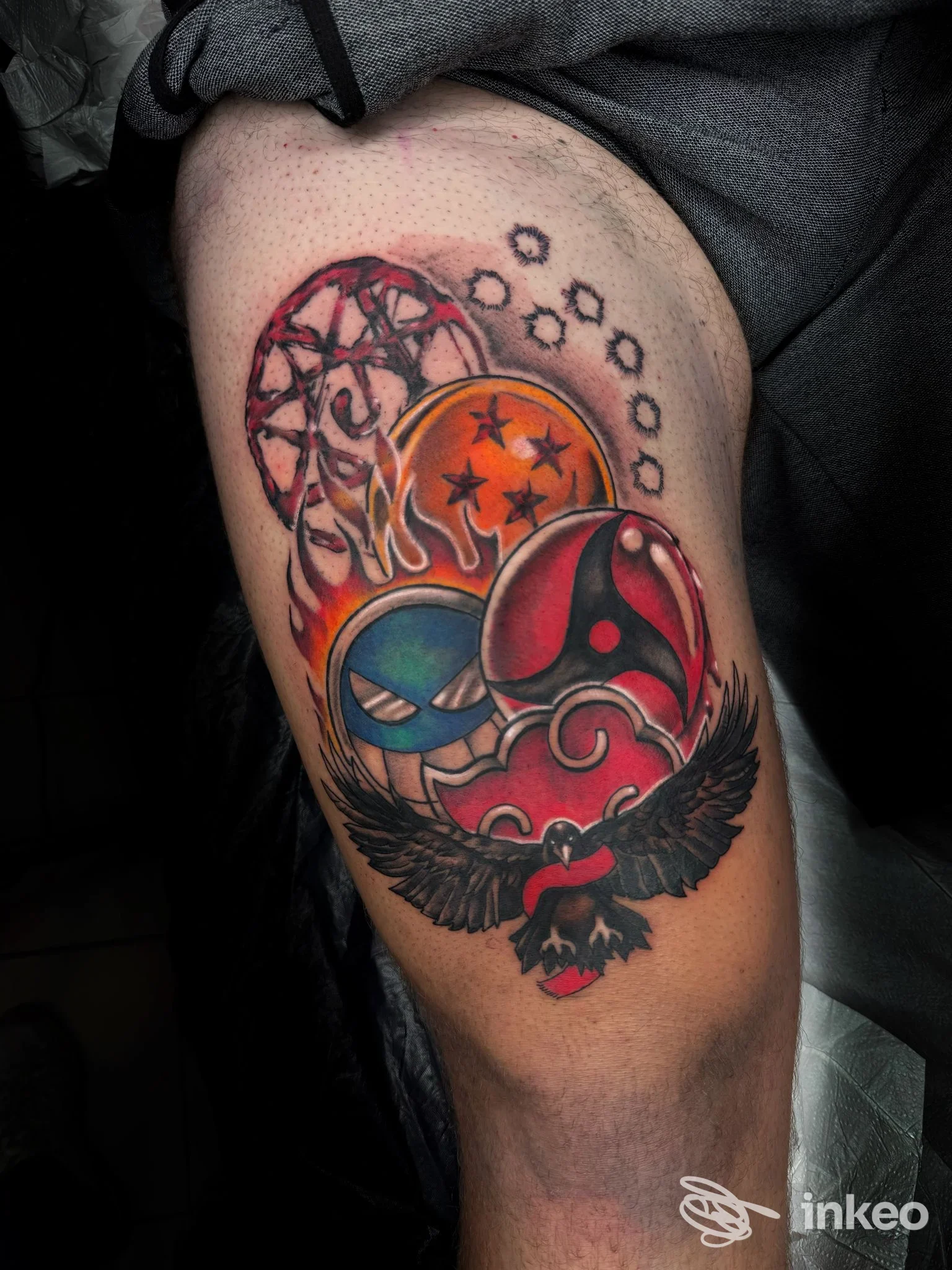 Tatuaggio colorato su braccio raffigurante maschere, stelle e un'aquila nera: tatuaggio completo su pelle visibile.