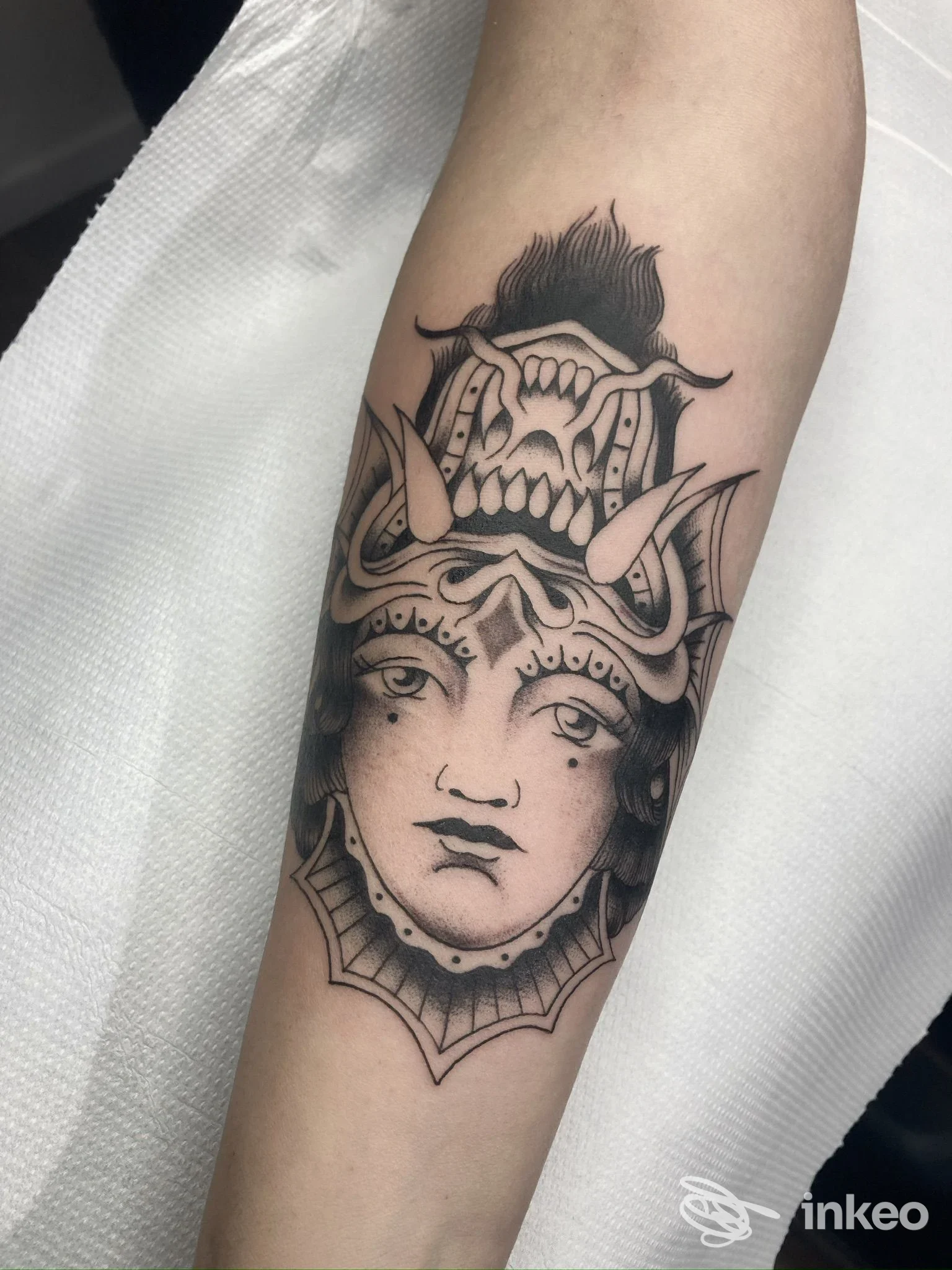 Tatuaggio in bianco e nero su avambraccio: volto stilizzato con elmo, foto fornita da SPINE Tattoo Lab, Torino.