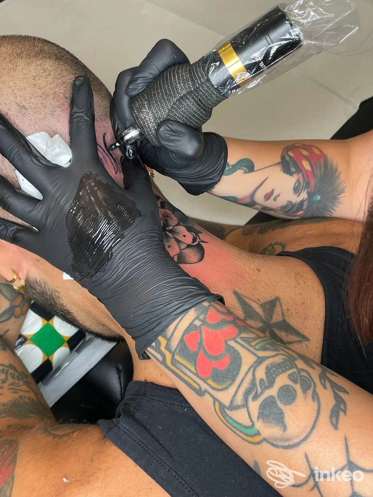 Tatuatore al lavoro sulla nuca di un cliente nello studio SPINE Tattoo Lab a Torino, ripresa ravvicinata della procedura.