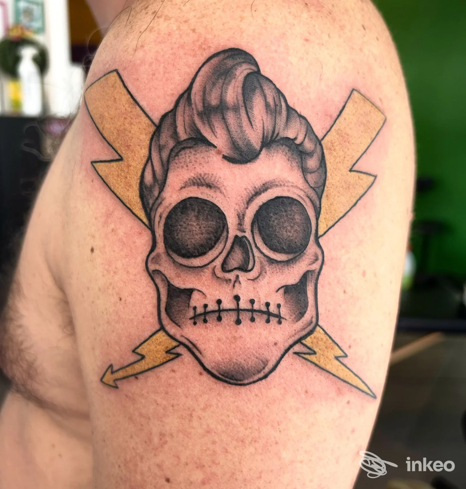 Tatuaggio su spalla con teschio stilizzato e fulmini gialli, foto di Strawberry ink tattoo studio a Nichelino.
