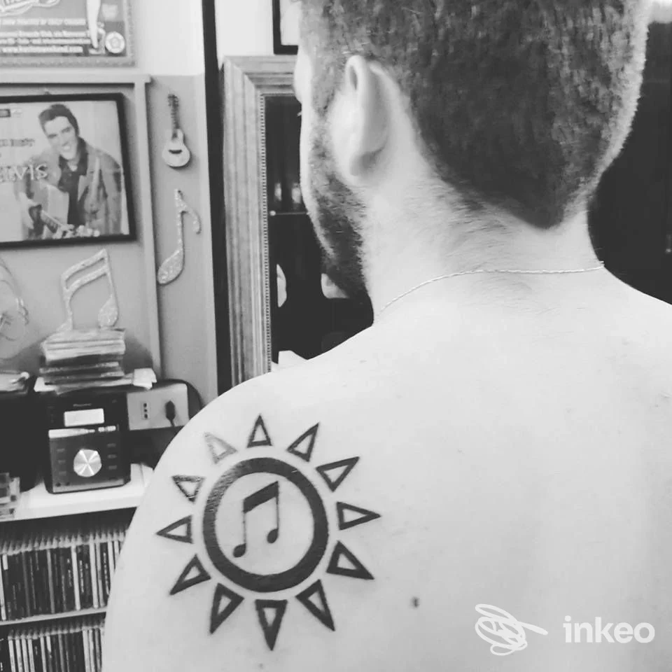 Uomo di spalle con tatuaggio a forma di sole e nota musicale sulla spalla sinistra. Tattoo Old Style by Johnny Cat, Torino.