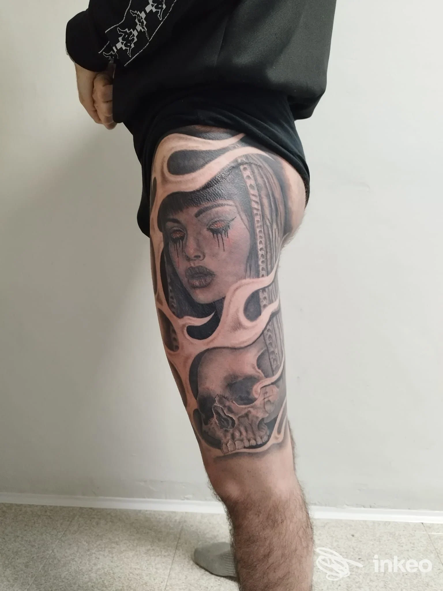 Tatuaggio realistico in nero e grigio su coscia, dettaglio volto e teschio. Tattoo Studio 220, Ivrea.