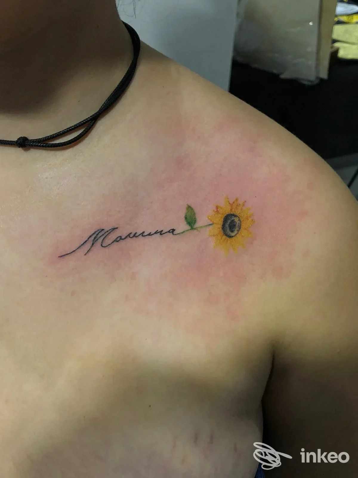 Fotografia di un tatuaggio sul pettorale con la scritta "Mamma" e un girasole colorato, realizzato da Tattoo mad ink a Moncalvo.