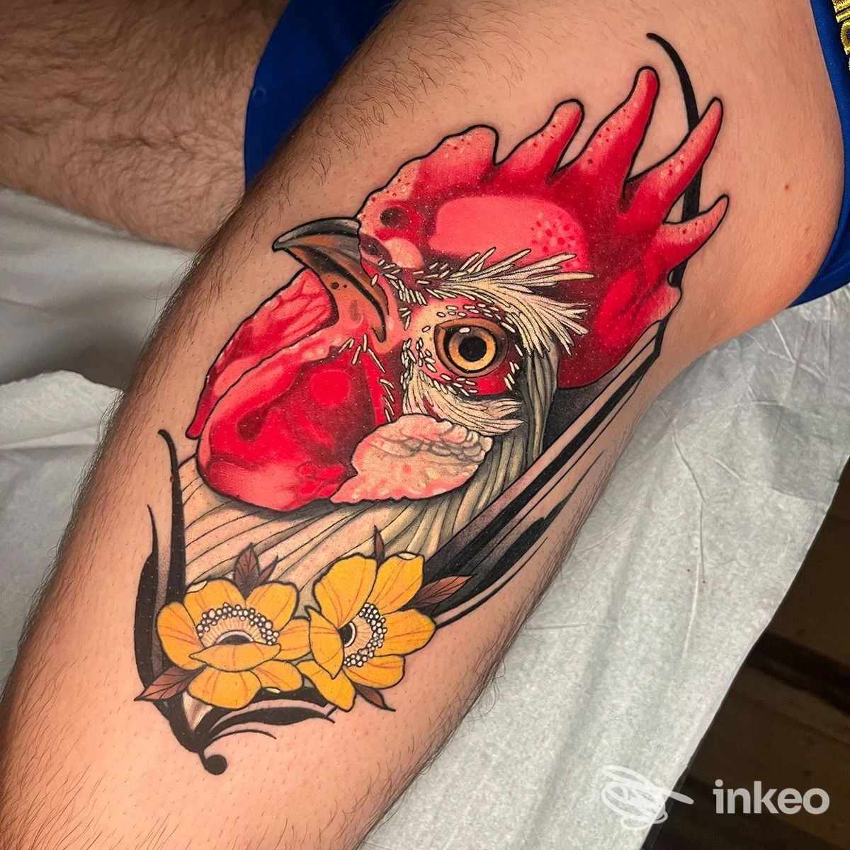Tatuaggio a colori di una testa di gallo con fiori gialli sulla coscia, foto fornita da MENOUNO Studio, Torino.