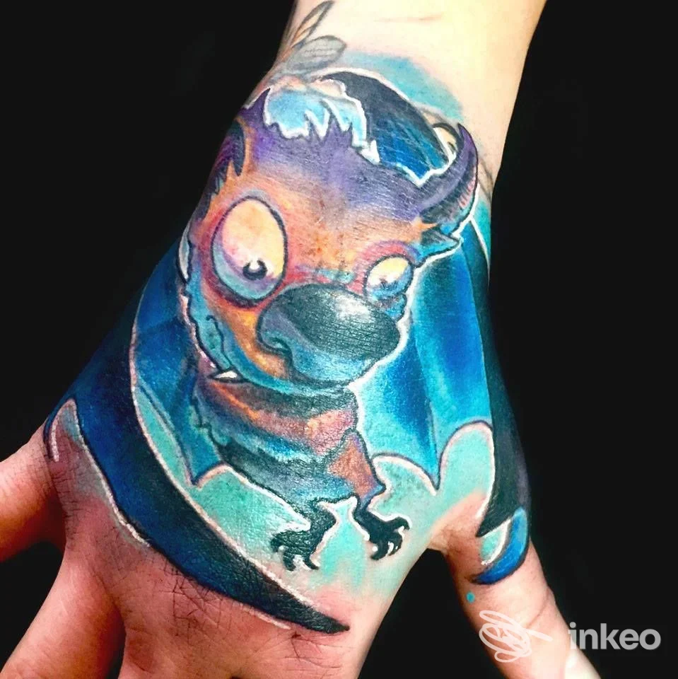 Tatuaggio colorato sul dorso della mano raffigurante una creatura stilizzata, WB Tattoos Art, Torino.