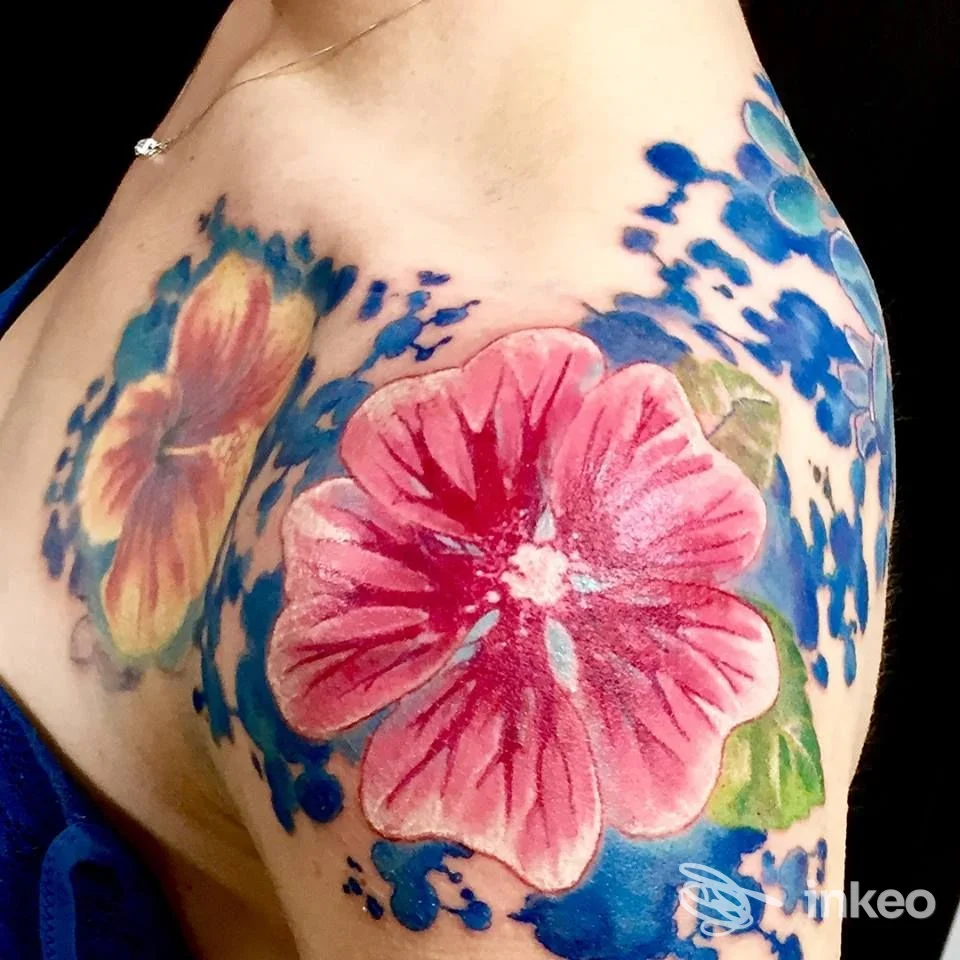Tatuaggio floreale a colori su spalla e petto, realizzato da WB Tattoos Art a Torino, con grande fiore rosa e riempimenti blu e verdi.