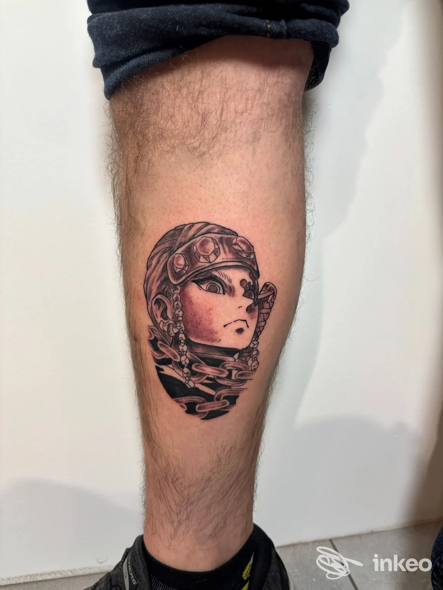 Tatuaggio stilizzato su polpaccio realizzato da Yugen tattoo studio, Torino: volto con casco e dettagli ornamentali su pelle.