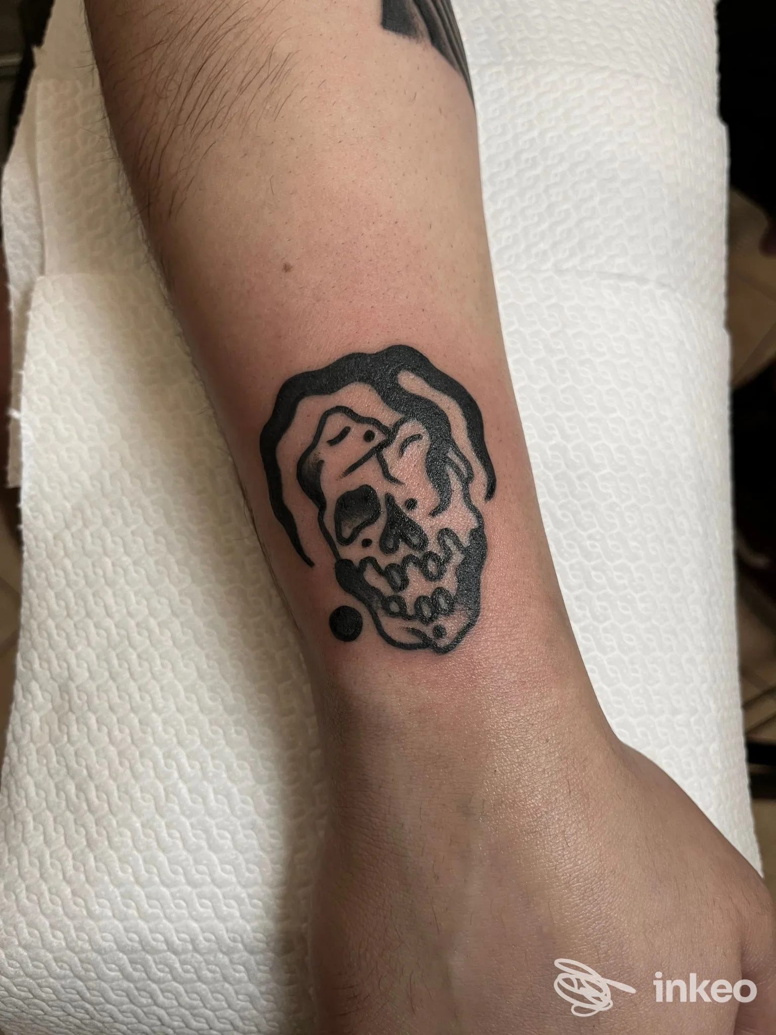 Primo piano di un tatuaggio cranio in nero sull'avambraccio eseguito da Veracruz Tattoo a Torino, pelle leggermente arrossata.